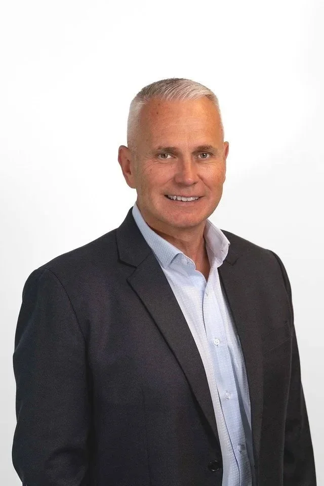 Portrait of a middle-aged man wearing a dark blue suit and light blue shirt against a plain white background.