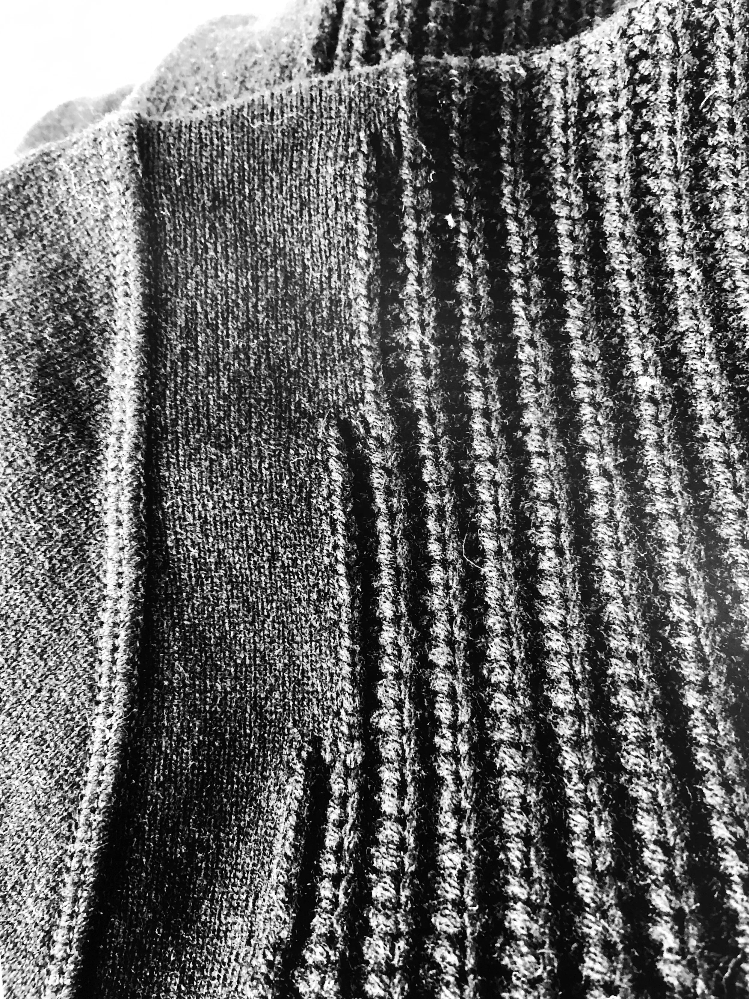 Close-up of exaggerated rib knit patterns in black and gray tones.