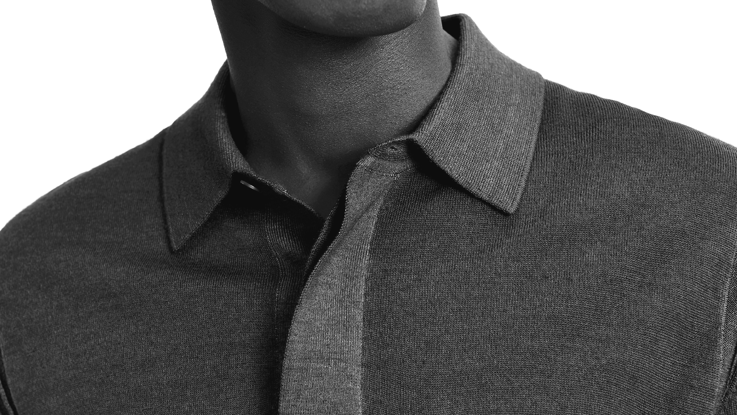 A close-up of a person's upper torso wearing a dark gray garment dyed knitted polo.