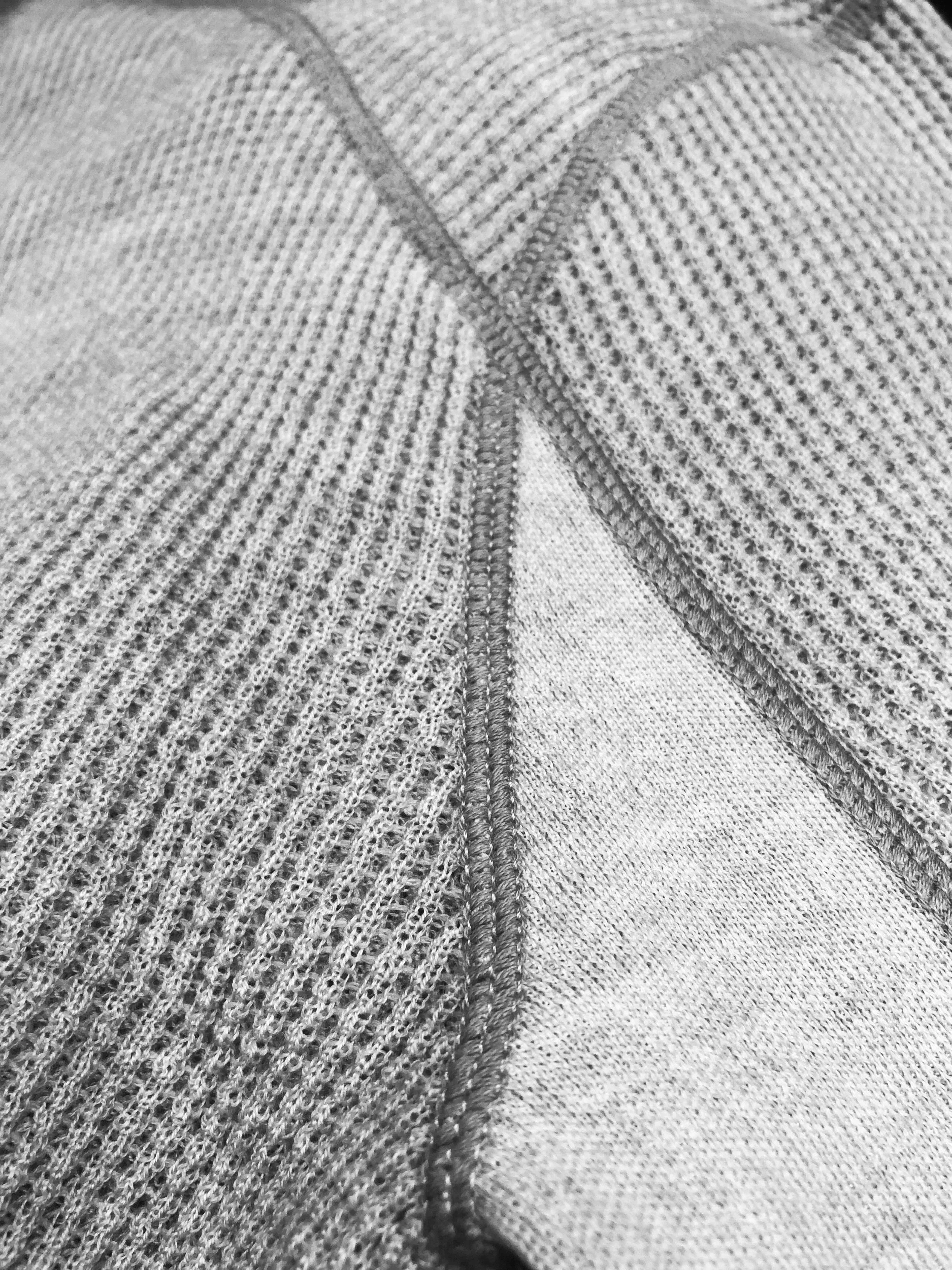 Close-up photo of a flat lock seam on a piece of waffle textured knitwear, showing detailed stitching and material pattern.