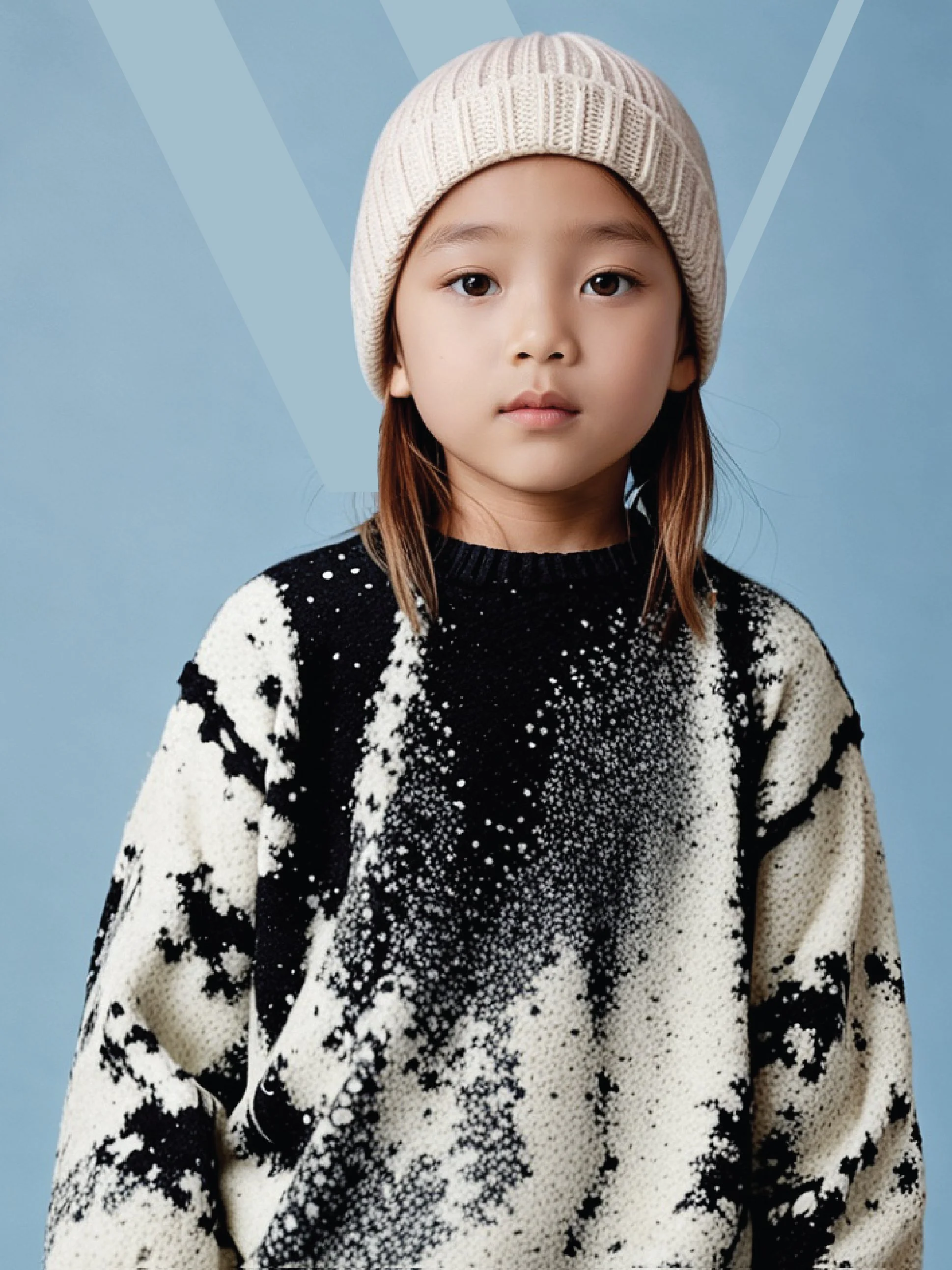Portrait of a young kid with straight brown hair wearing a beige knit beanie and a black and white patterned sweater against a blue background.