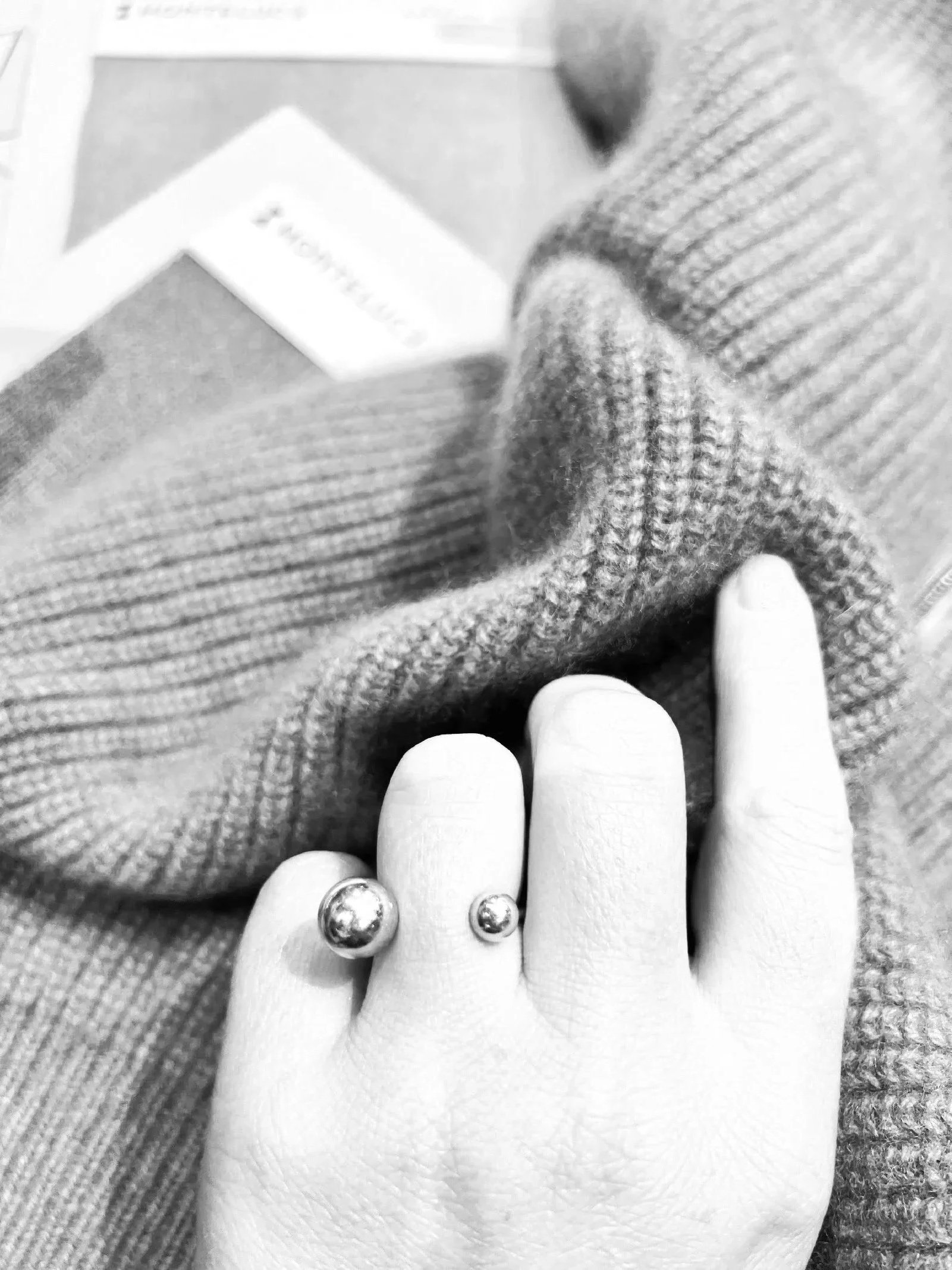 Close-up of a hand with two ball ring, touching a knitted rib textured sweater, textured surface.