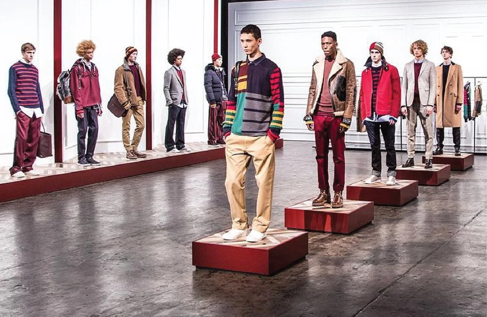 Mannequins displaying colorful casual clothing in a retail store, with some mannequins on red platforms and others in the background.