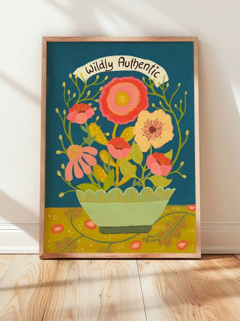A cheerful illustrated art print featuring a bouquet of colourful wildflowers in a scalloped bowl, set against a deep teal background with the words "Wildly Authentic" on a ribbon banner.