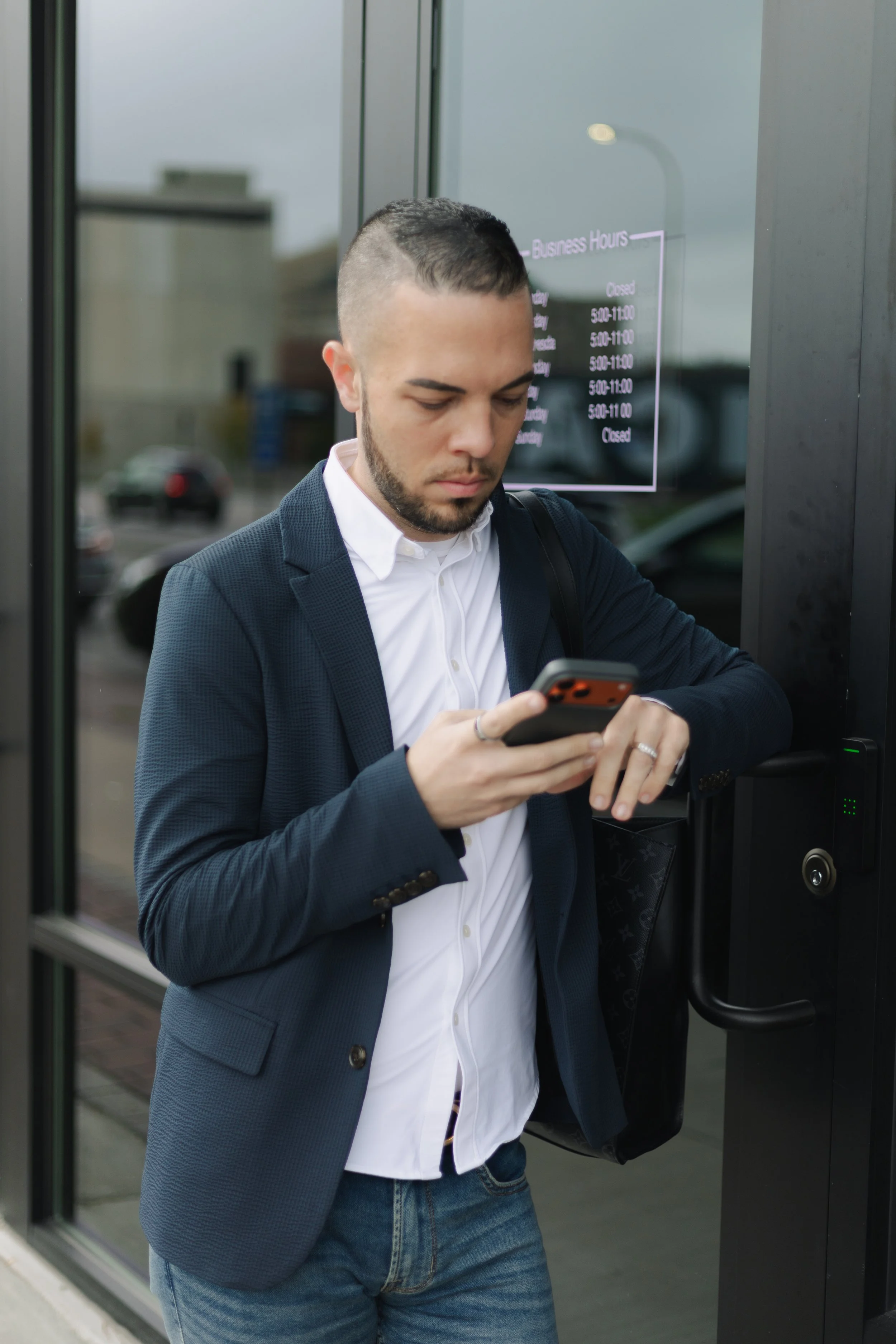 Tyler Young, founder of Click Command Co., standing in front of his restaurant managing social media on his phone, representing the done-for-you digital marketing services offered for small business owners in wellness, hospitality, and real estate