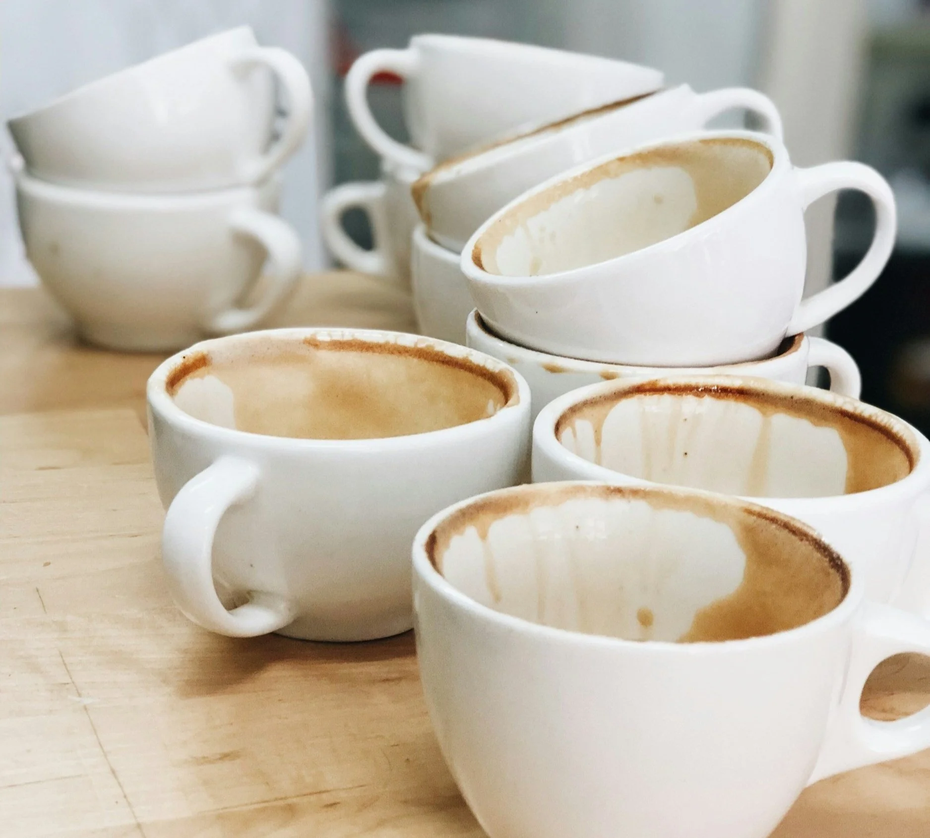 A stack of white dirty coffee cups, highlighting the importance of avoiding clutter by cleaning as you go.