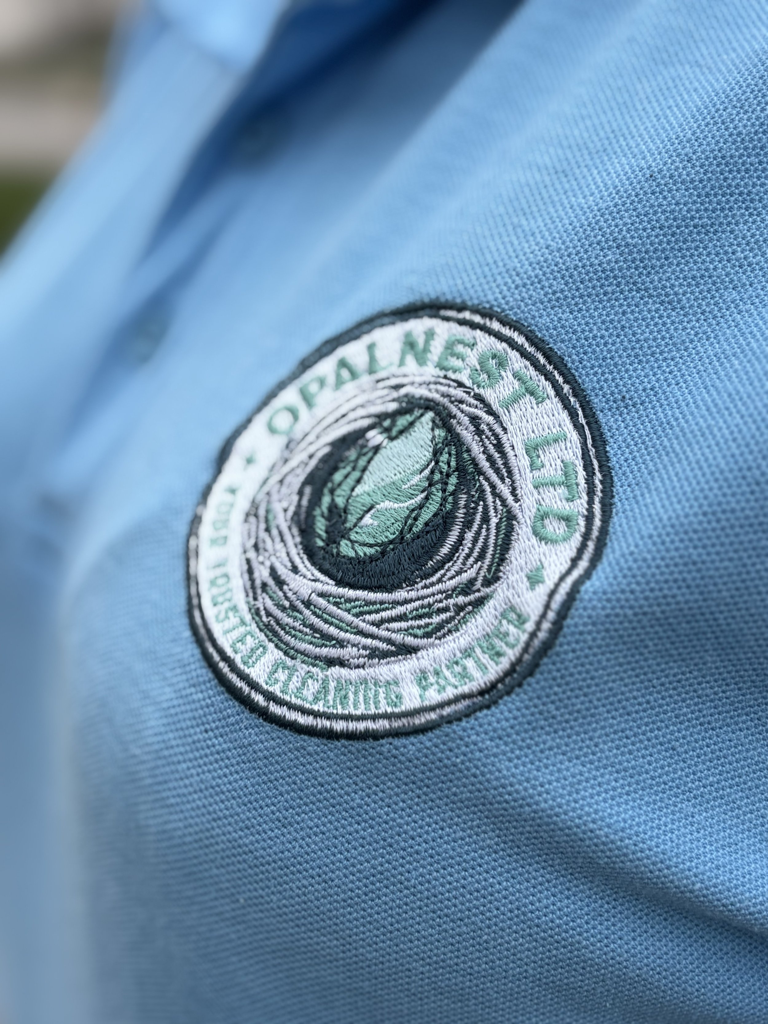 OpalNest embroidered logo on on turquise polo shirt.