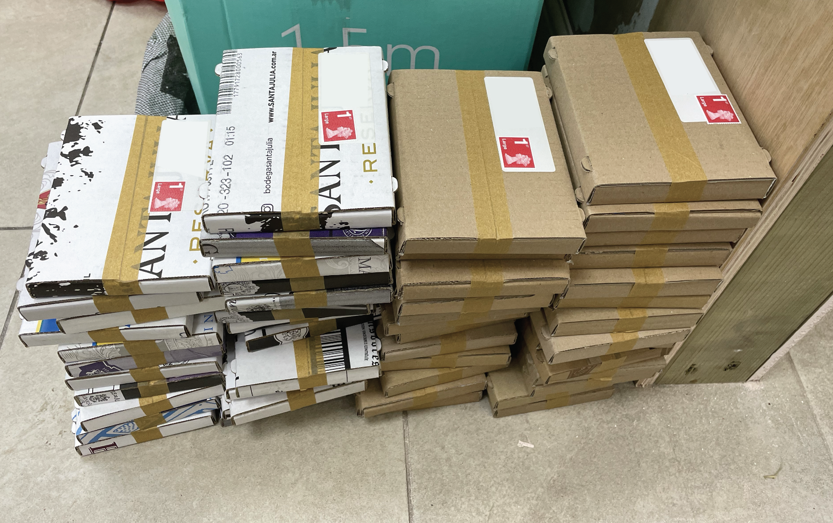 Stacked cartons and boxes in a store with delivery labels and tape.