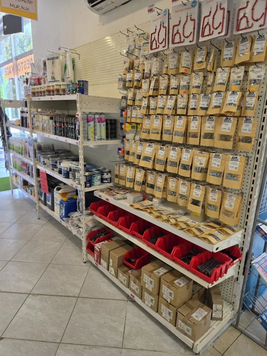 étagères avec divers produits de bricolage, notamment des vis, des clous et des gants, dans un magasin de quincaillerie.