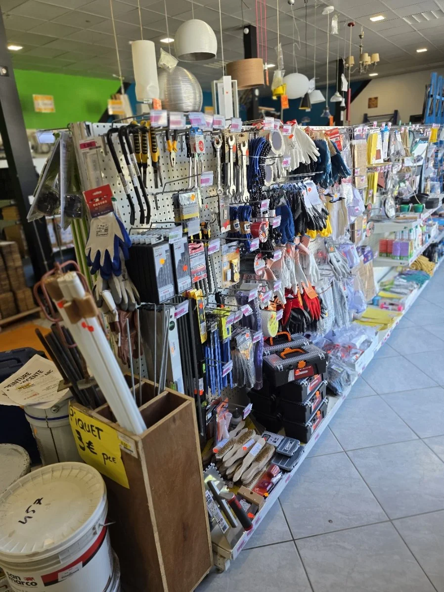 Rayonnage avec des outils, gants, lumières, et autres articles de bricolage dans un magasin.