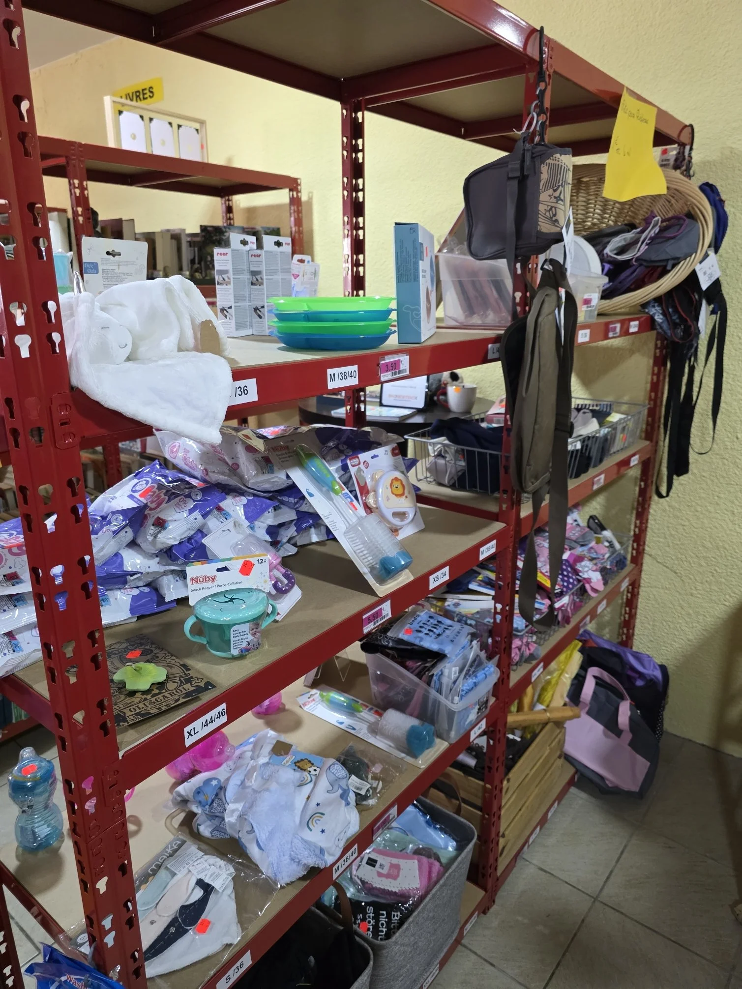 Rayonnage rempli de produits pour bébés tels que couches, tétines, jouets, sacs à langer et autres accessoires.