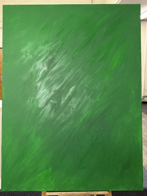 A large green canvas or board with textured brush strokes, leaning against a wall in an indoor setting.