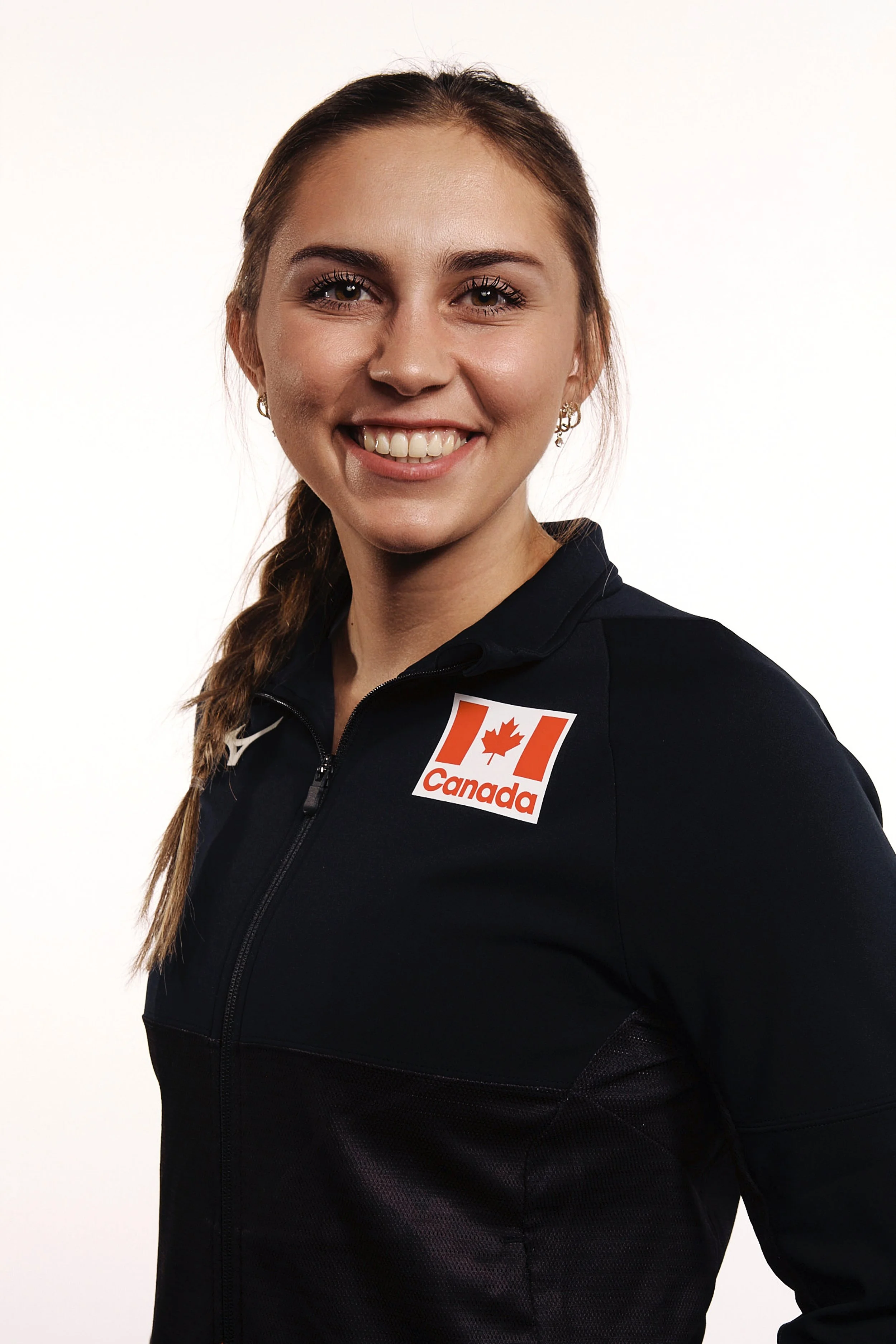 Portrait of a smiling woman with braided hair, wearing a black sports jacket with a Canada logo.