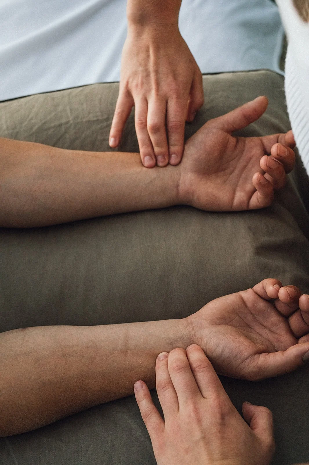 Two people providing a massage on a person's arm and wrist.