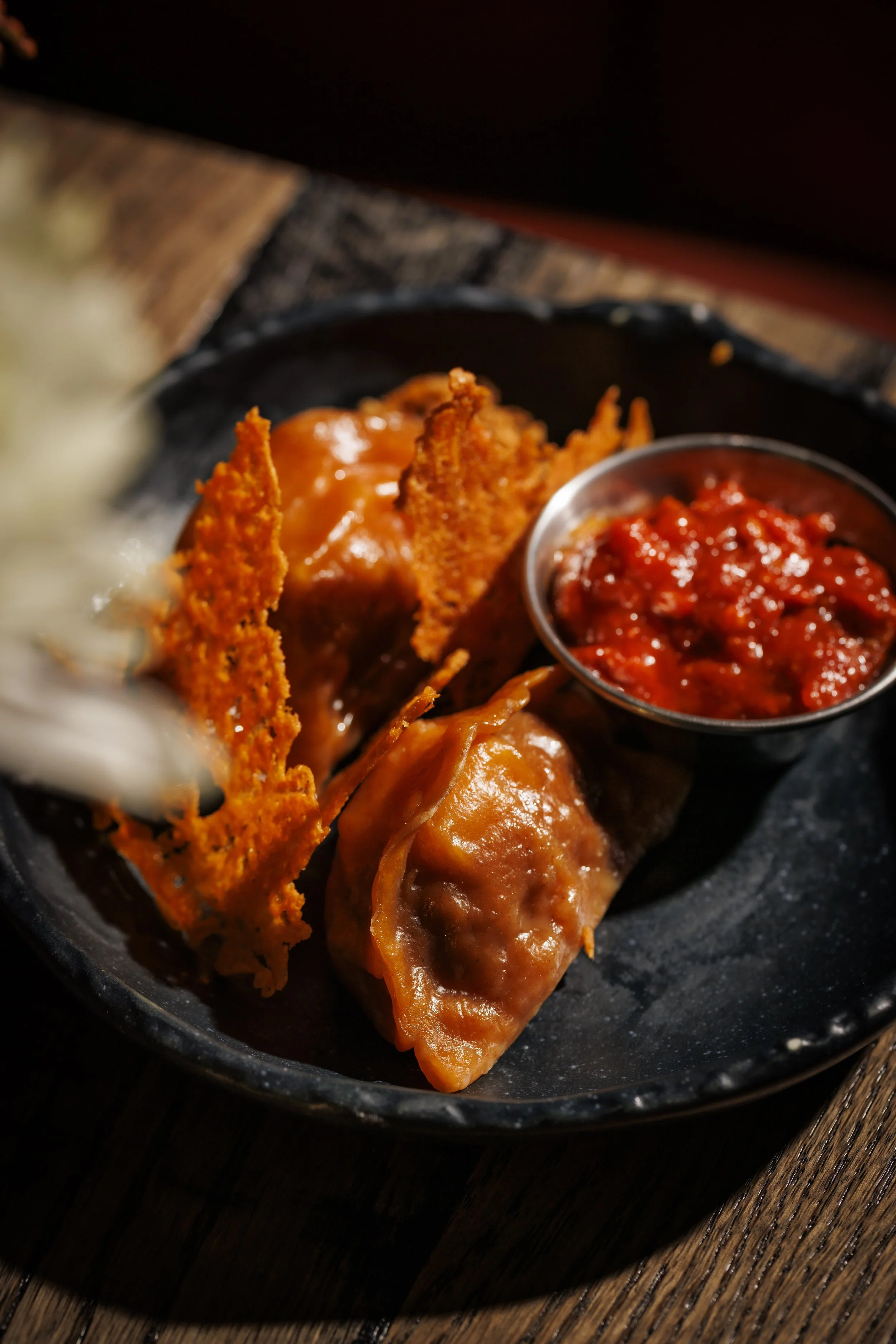 Fried chicken drumsticks with gravy and a side of salsa on a black plate.