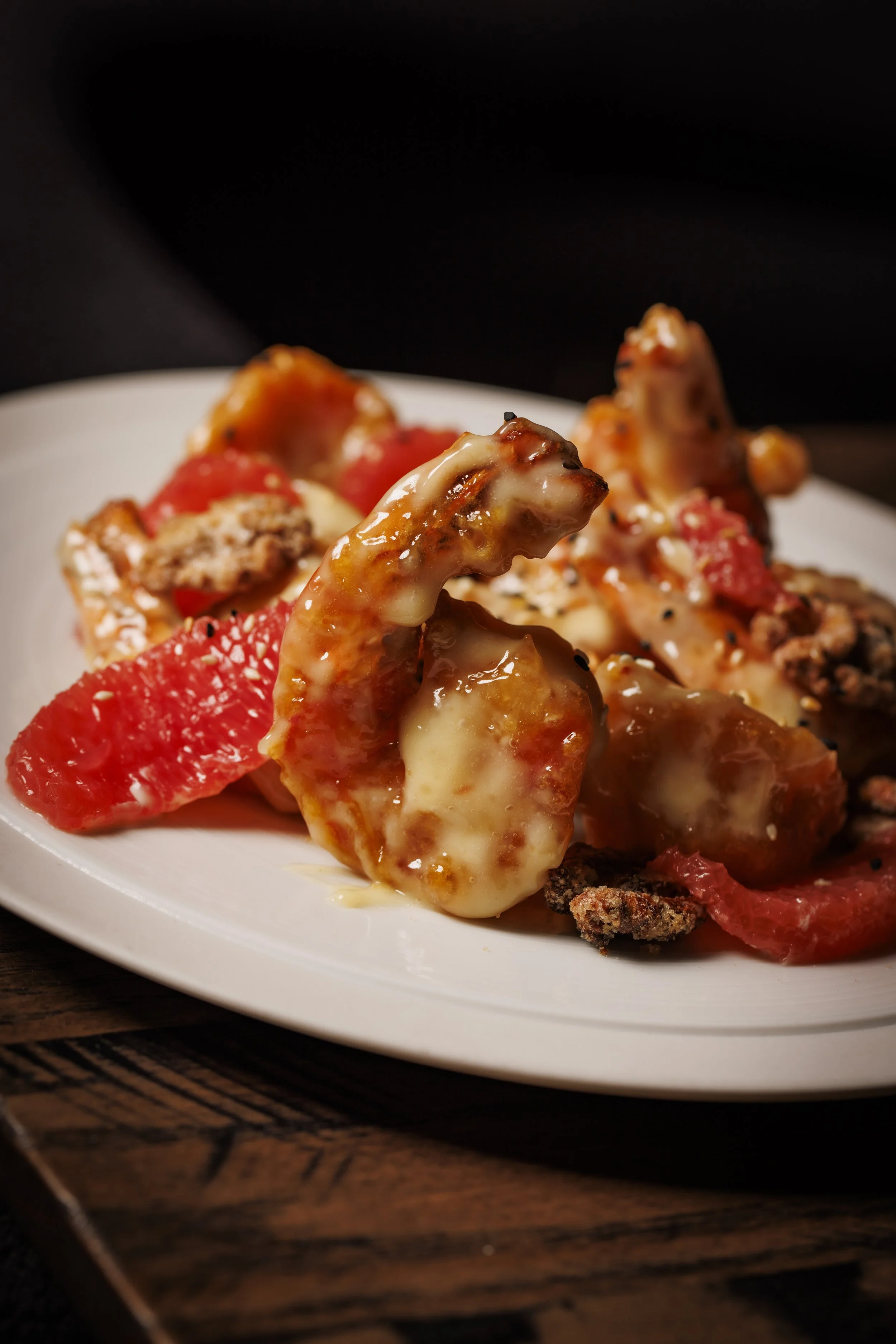 Close-up of a plate of nachos with melted cheese, chopped tomatoes, and beef on a wooden surface.