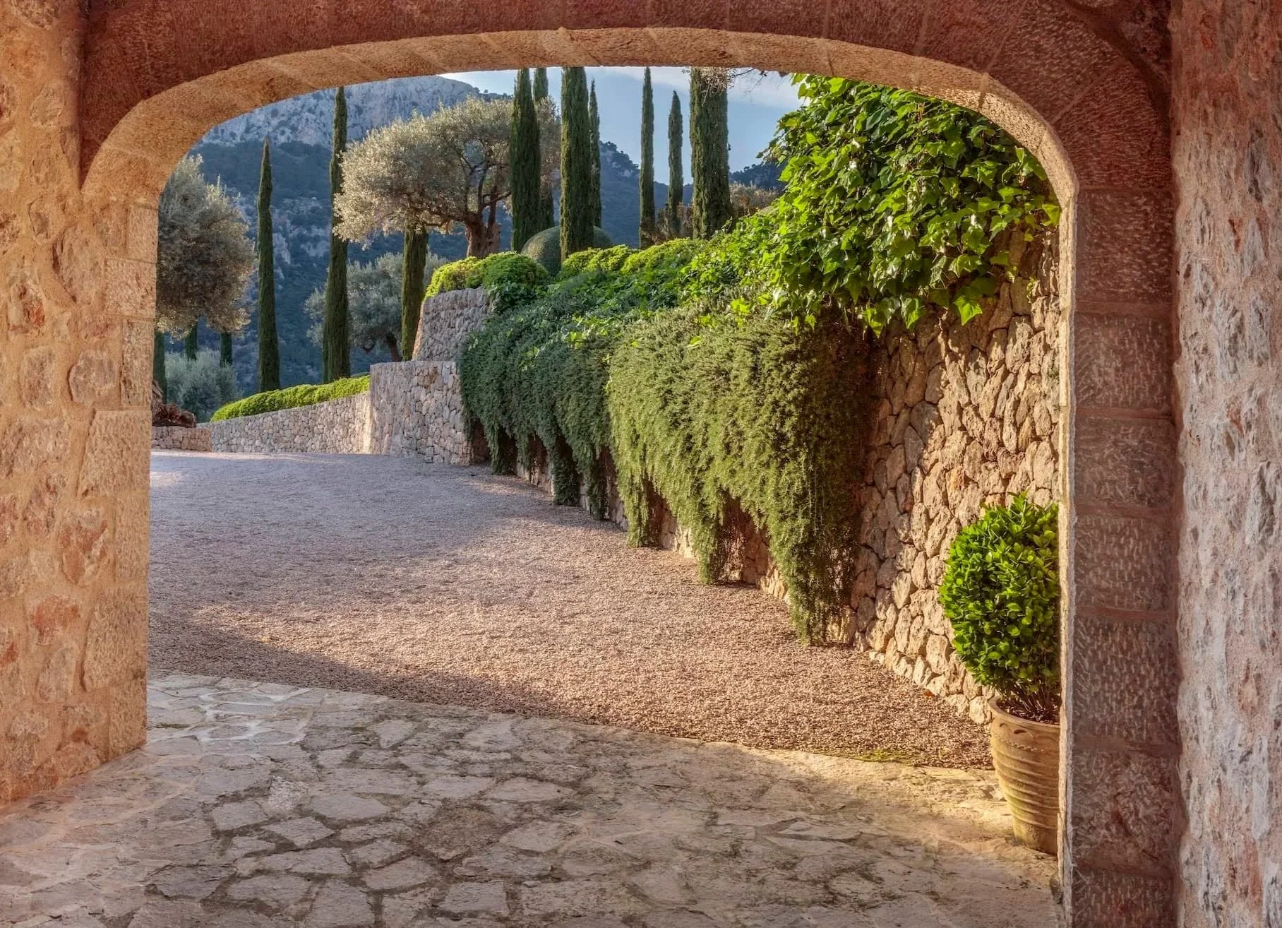 Stone archway framing a cypress-lined drive, classically Mediterranean garden design Mallorca