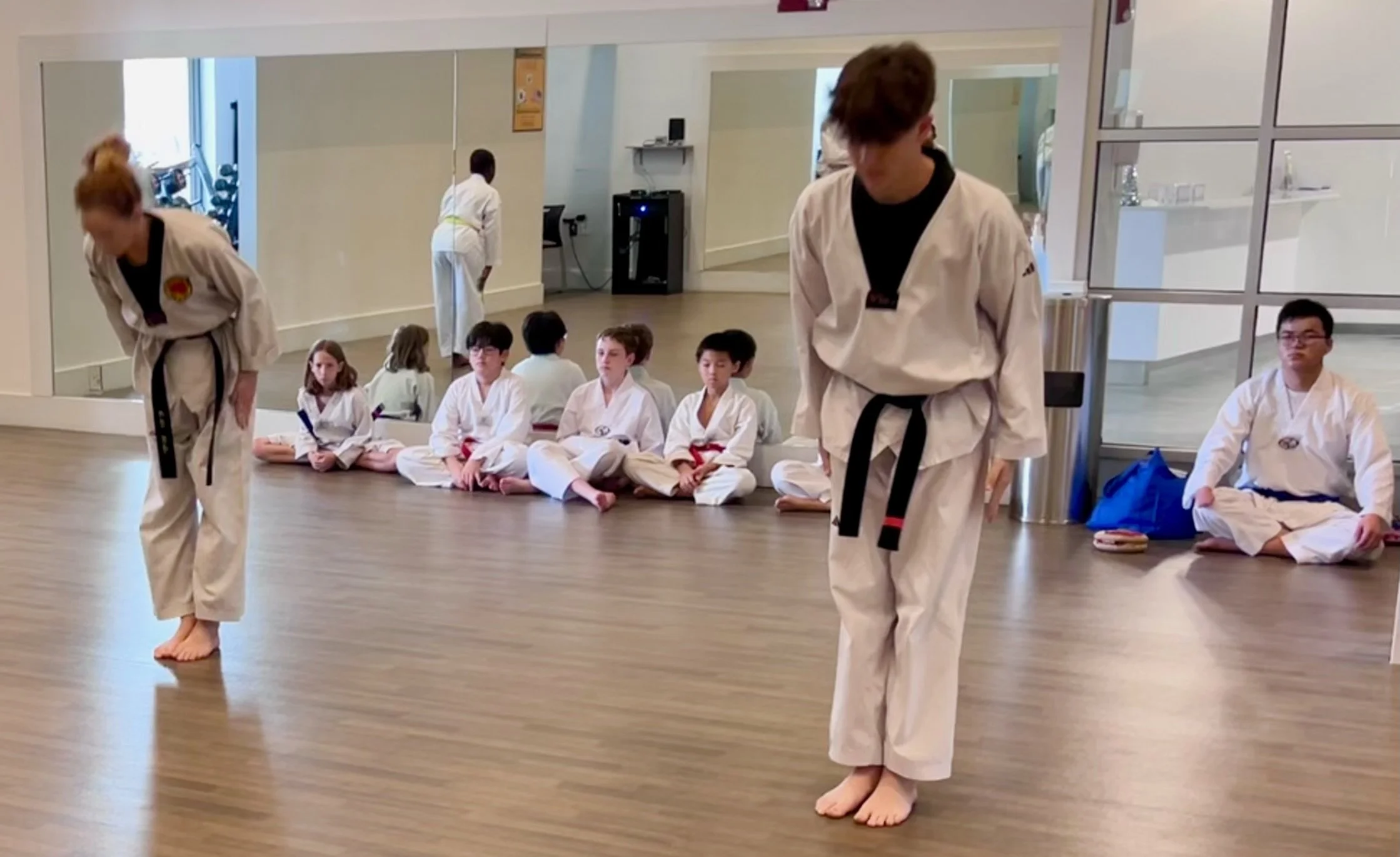 Two black belt students bow forward. 