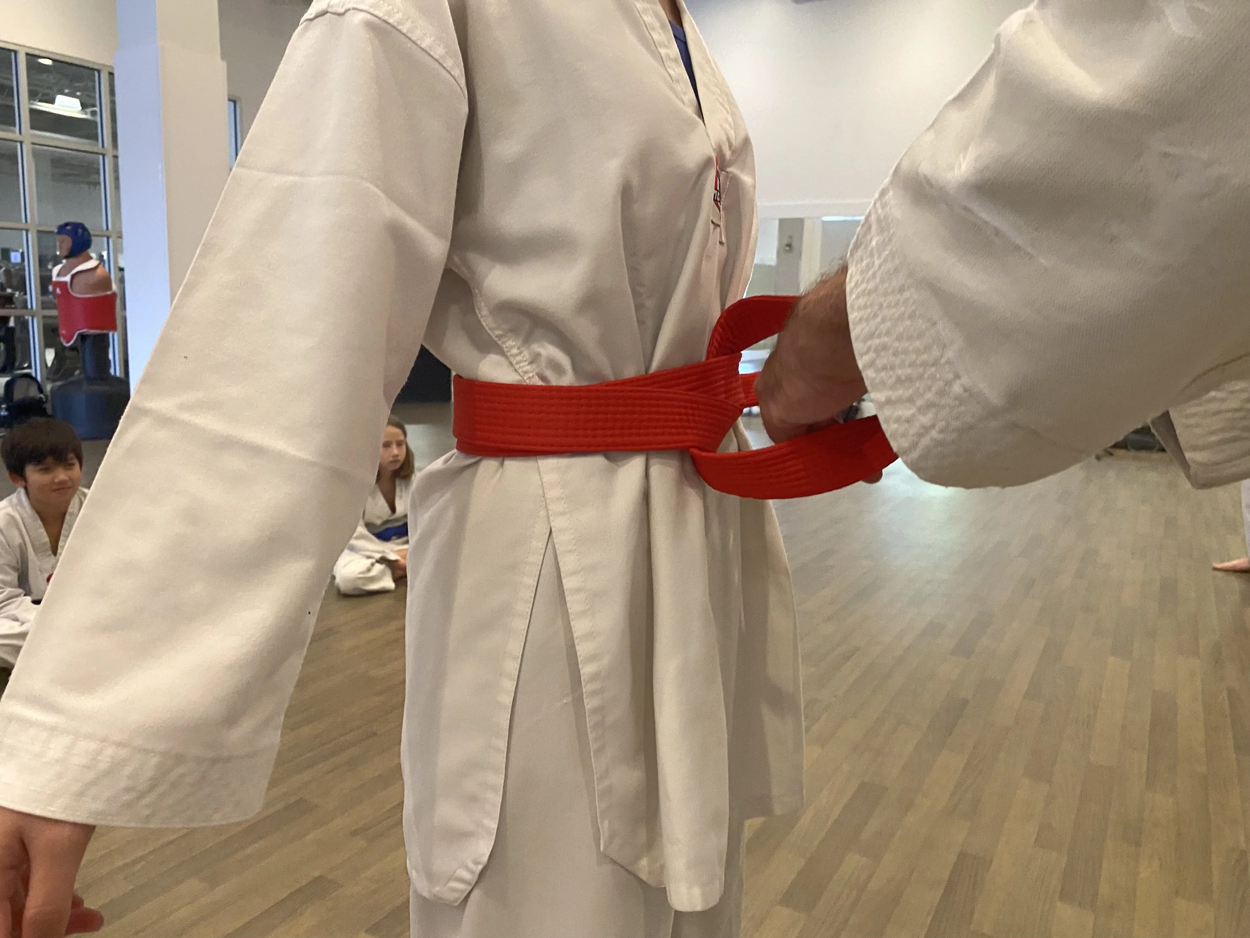 Tying a red belt around a student's waist
