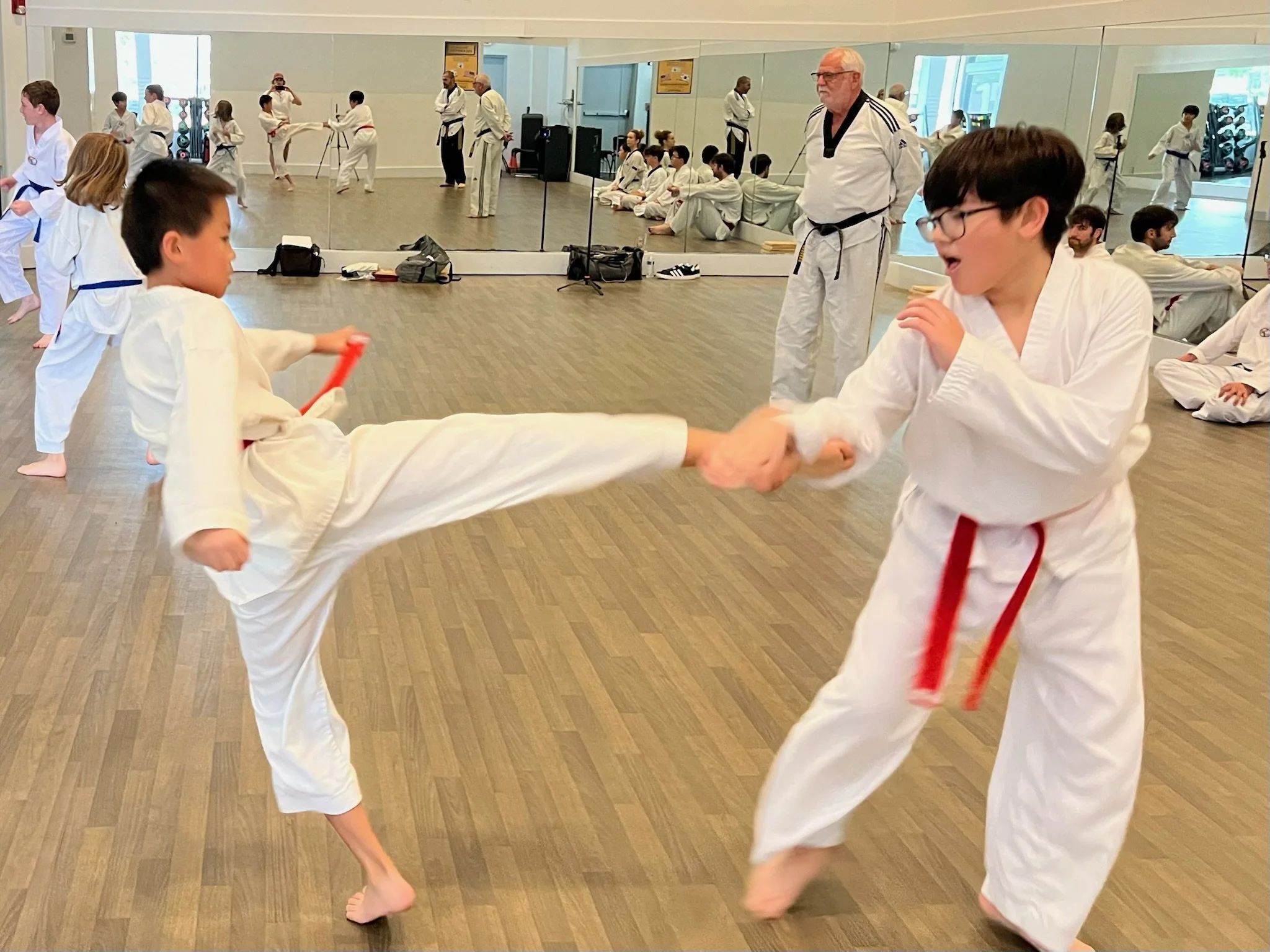 Orange belt boy kicks another boy with an orange belt while in taekwondo class. 