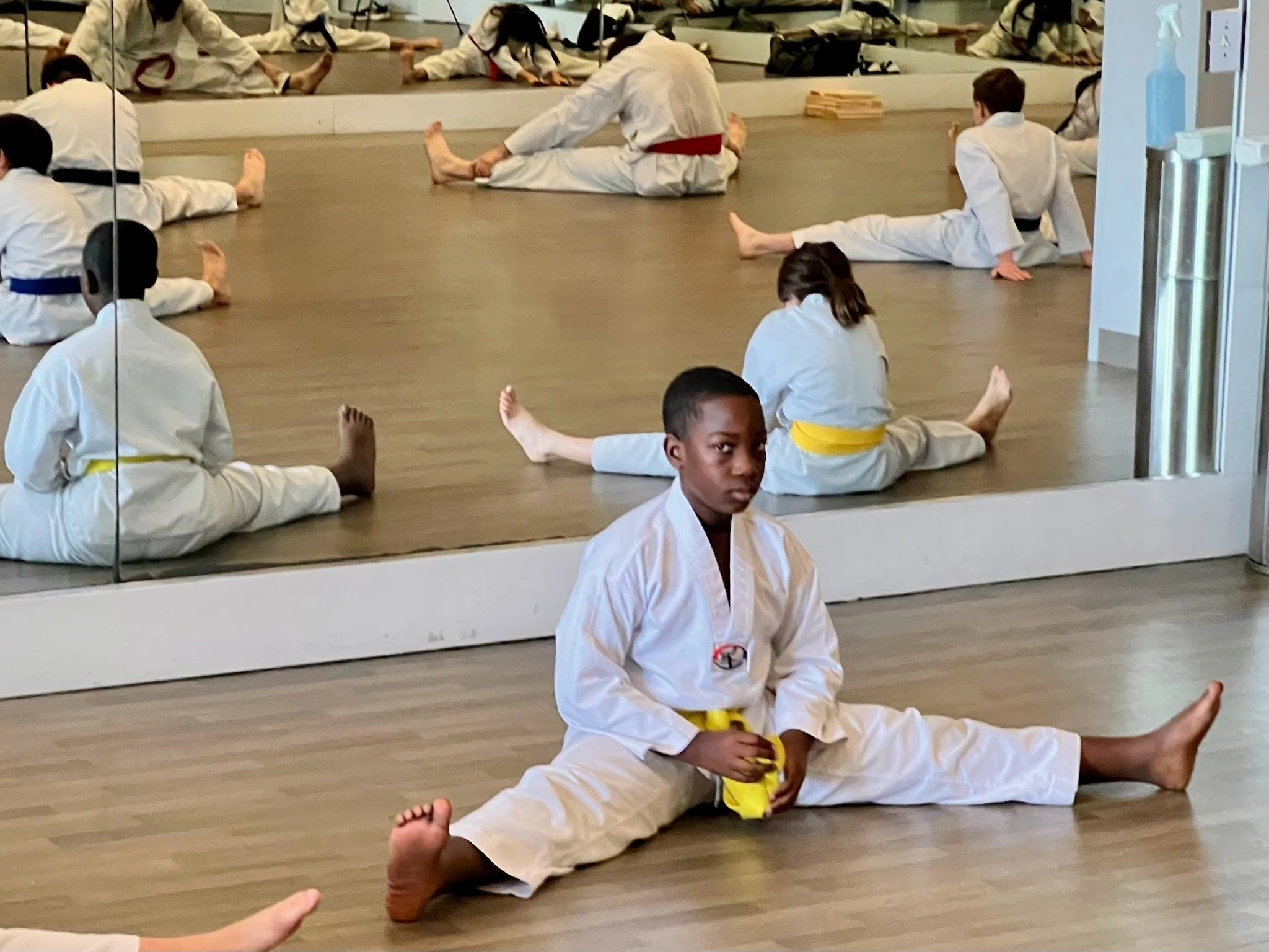 Male student with a yellow belt does stretch split.