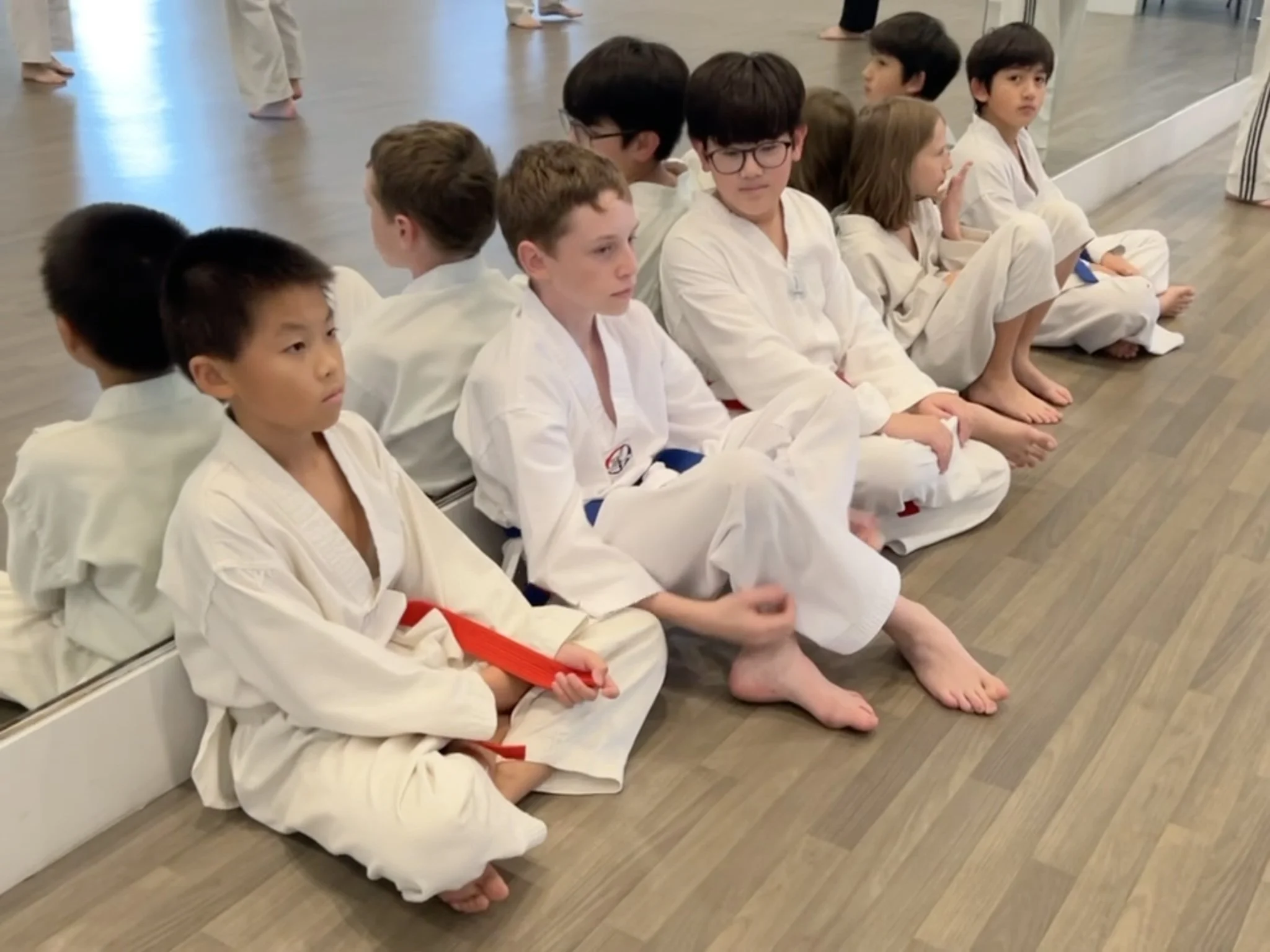 Student wearing uniforms sitting against mirror. 