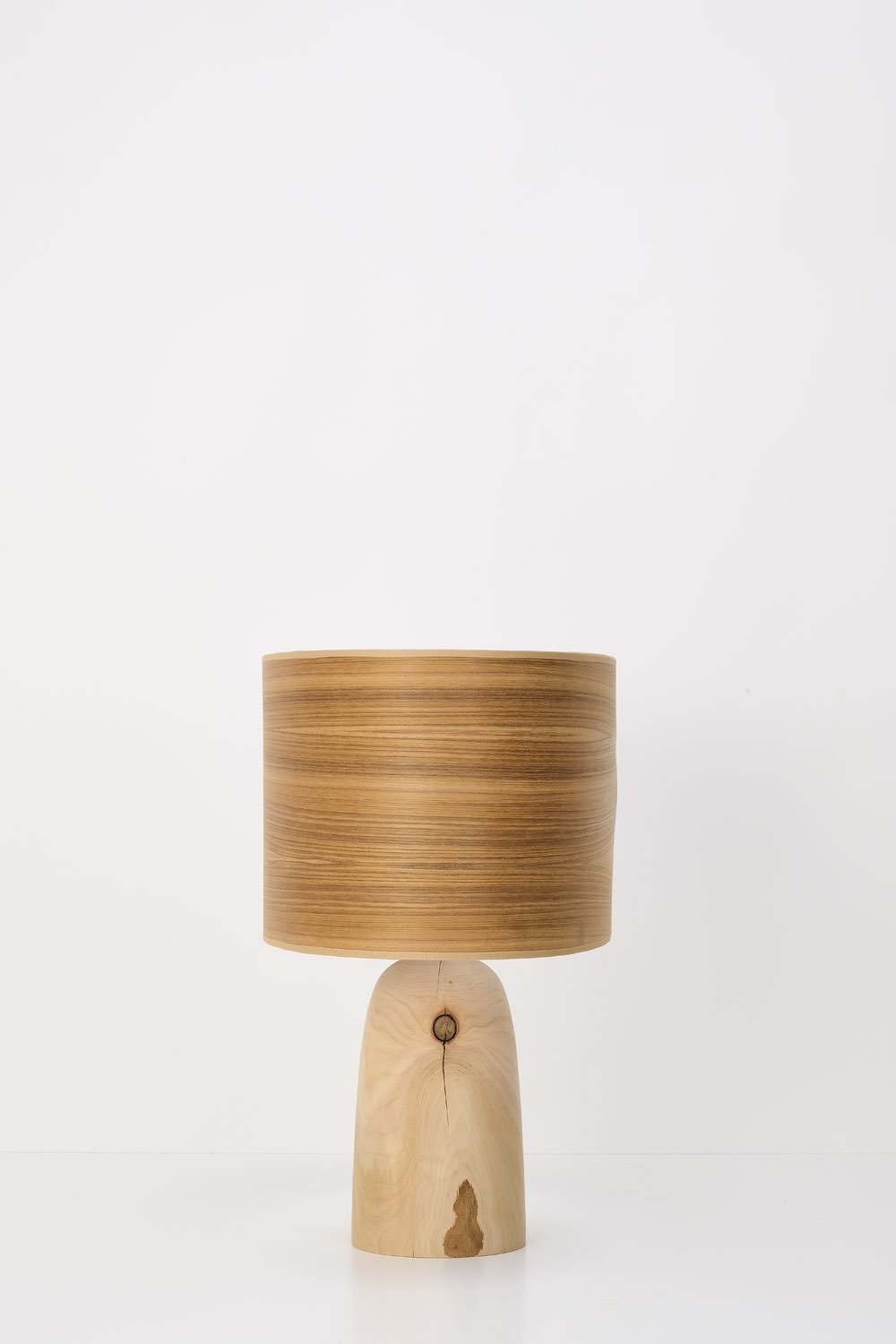 Wooden table lamp with a cylindrical shade and a carved wooden base.
