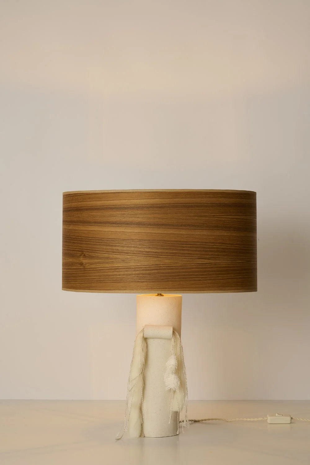 Table lamp with a white base and a brown cylindrical lampshade on a white surface against a plain white background.