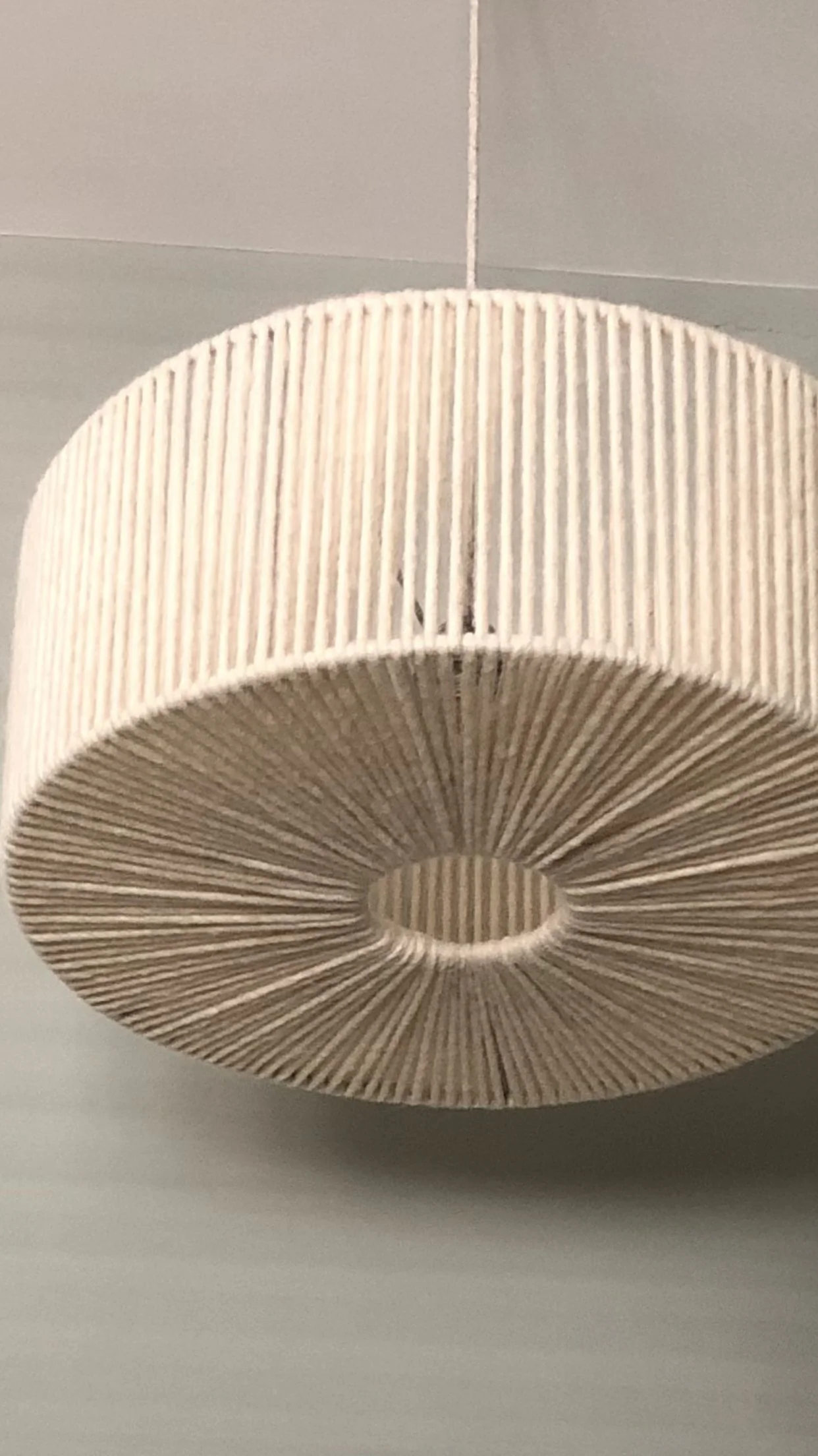 A hanging lampshade with vertical slats, showing a round shape with a hollow center.