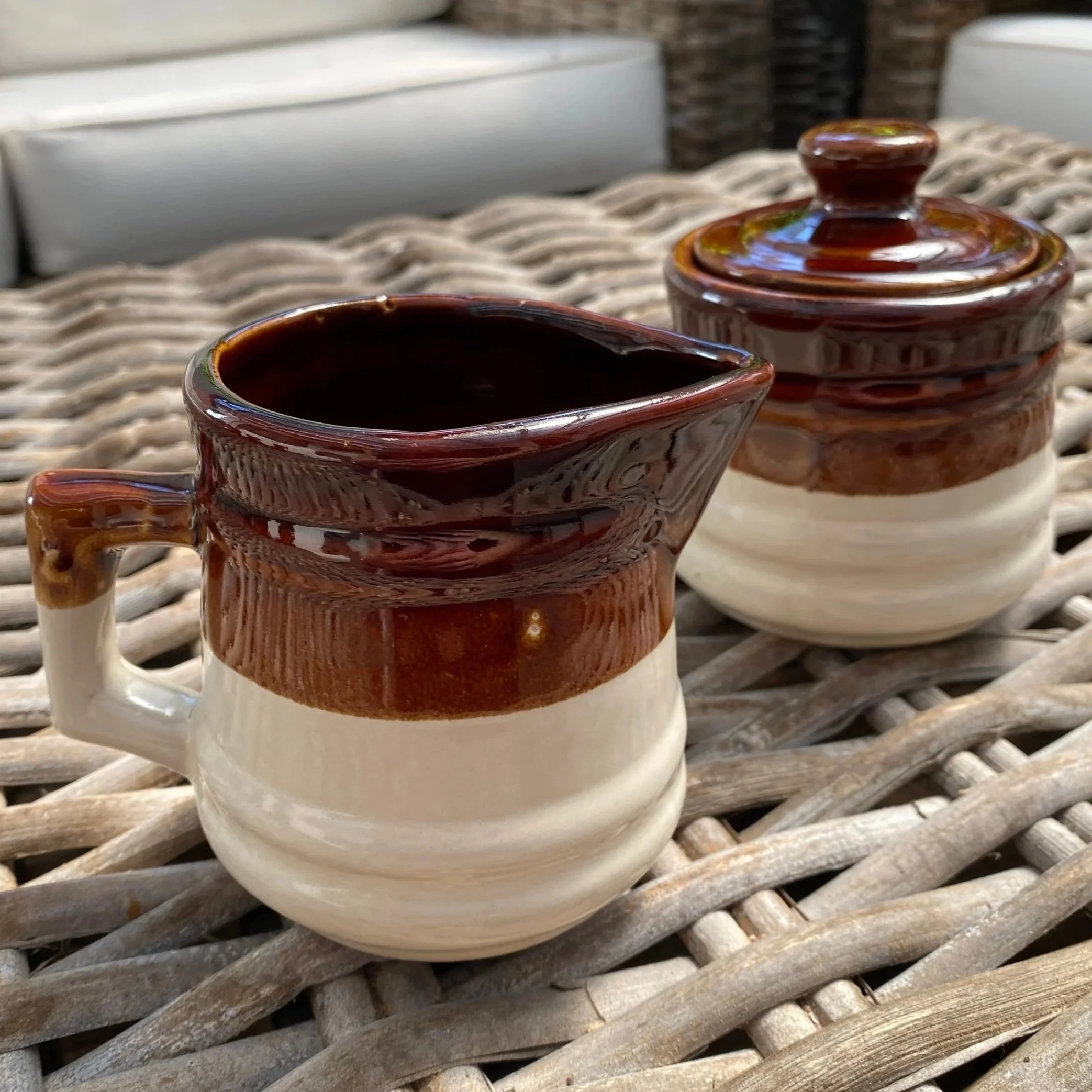 Creamer and sugar bowl side-by-side on a wicker surface showing warm two-tone glaze