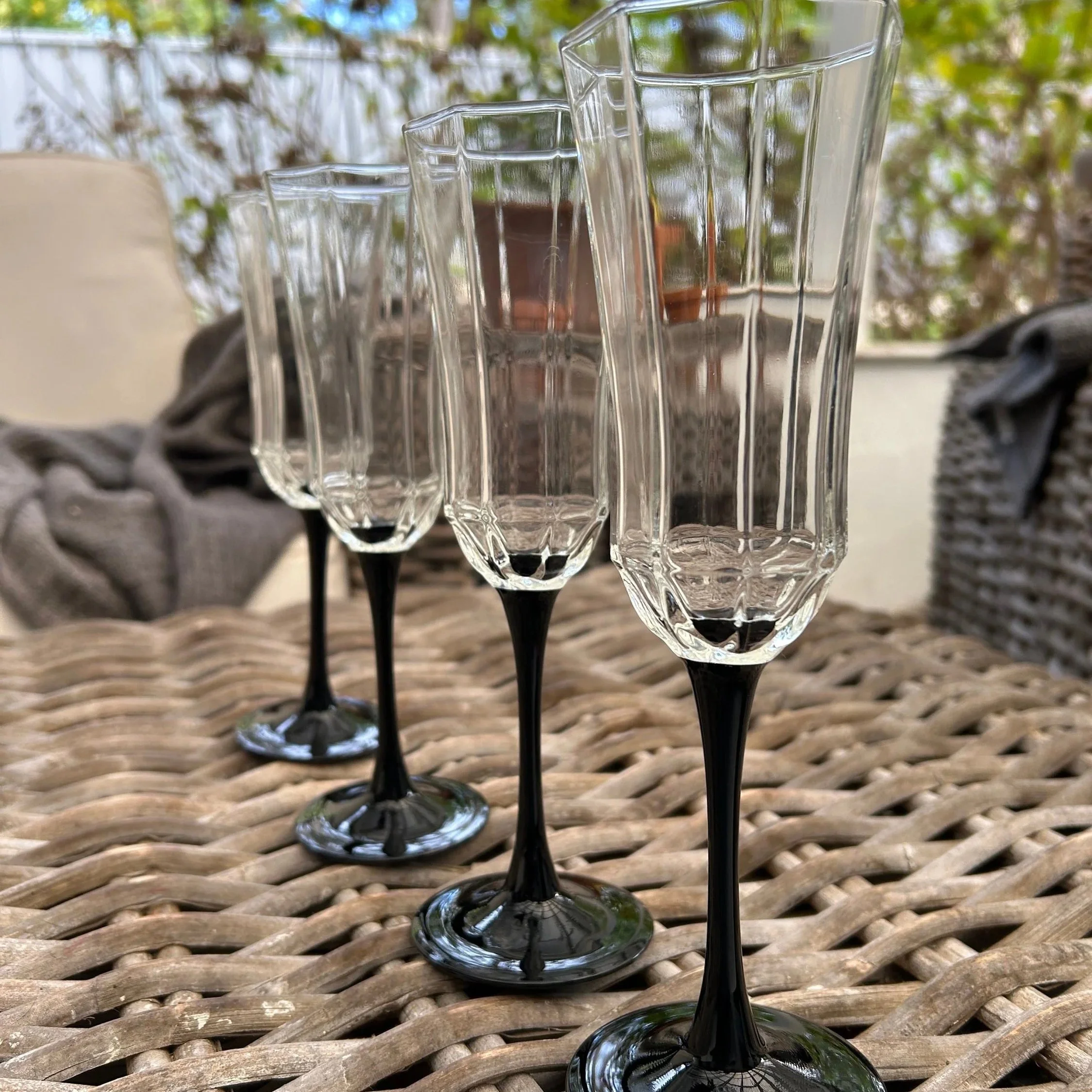 Set of four Luminarc Octime Black champagne glasses displayed on wicker table