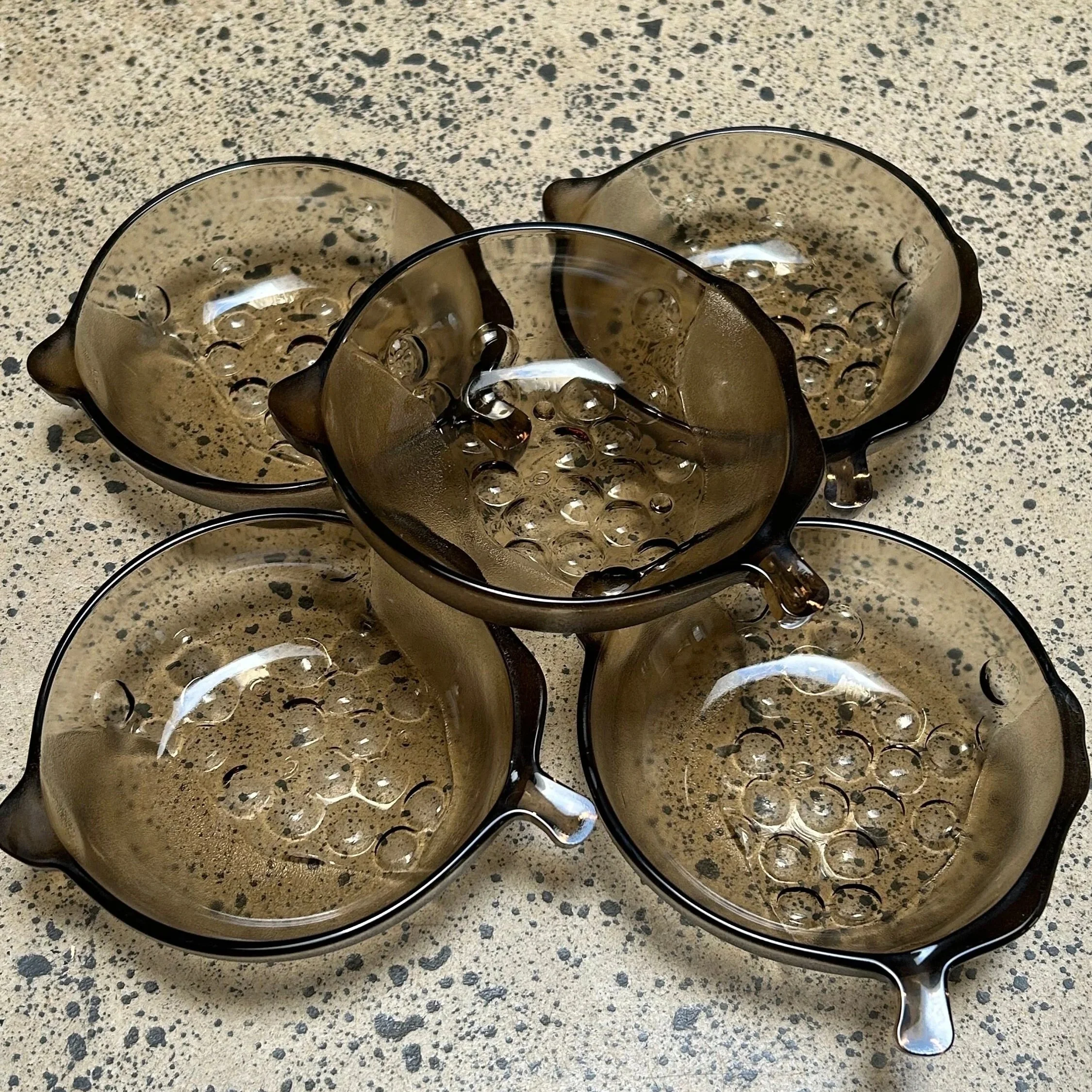 Overhead view of 5 vintage grey glass dessert bowls arranged in a circle