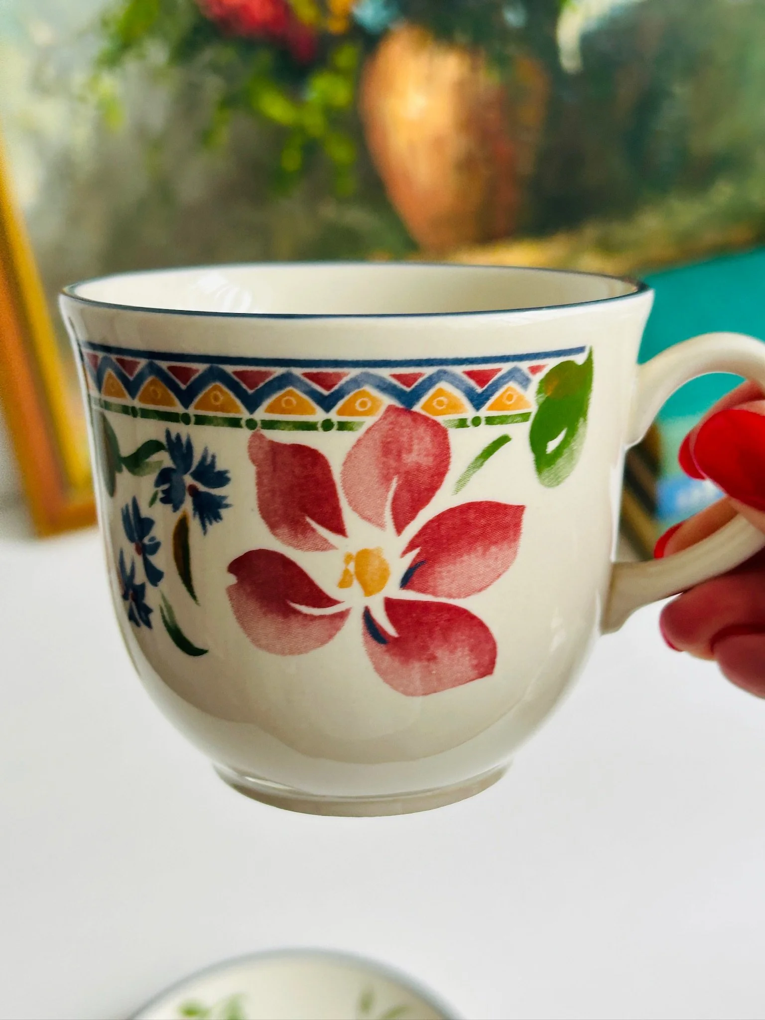 Close-up of the Staffordshire ‘Calypso’ tea cup held in hand, focusing on the large pink flower motif, geometric border, and glossy vintage finish.