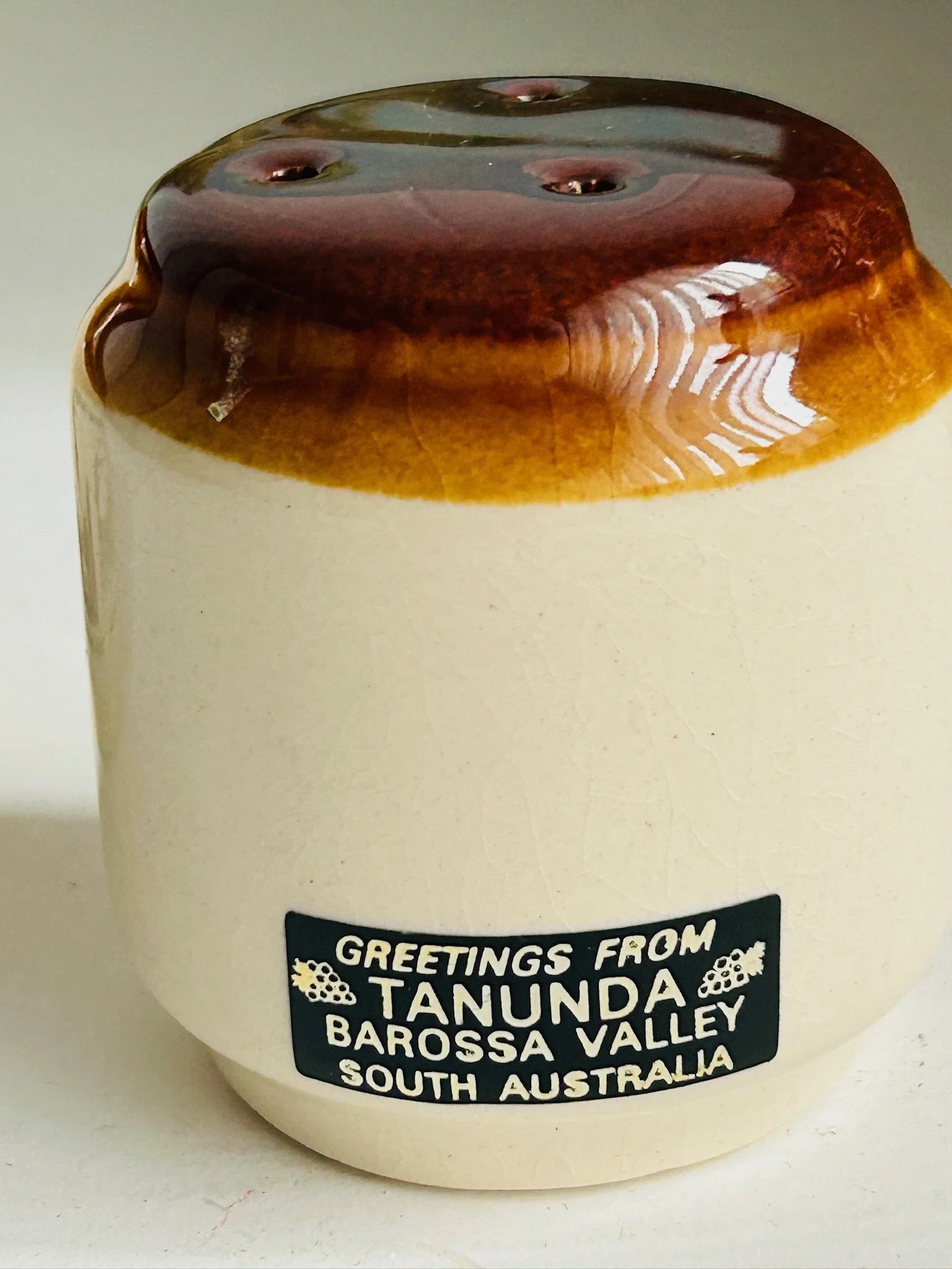 Rear view of one shaker showing the black “Greetings from Tanunda Barossa Valley South Australia” label on the plain cream stoneware side.