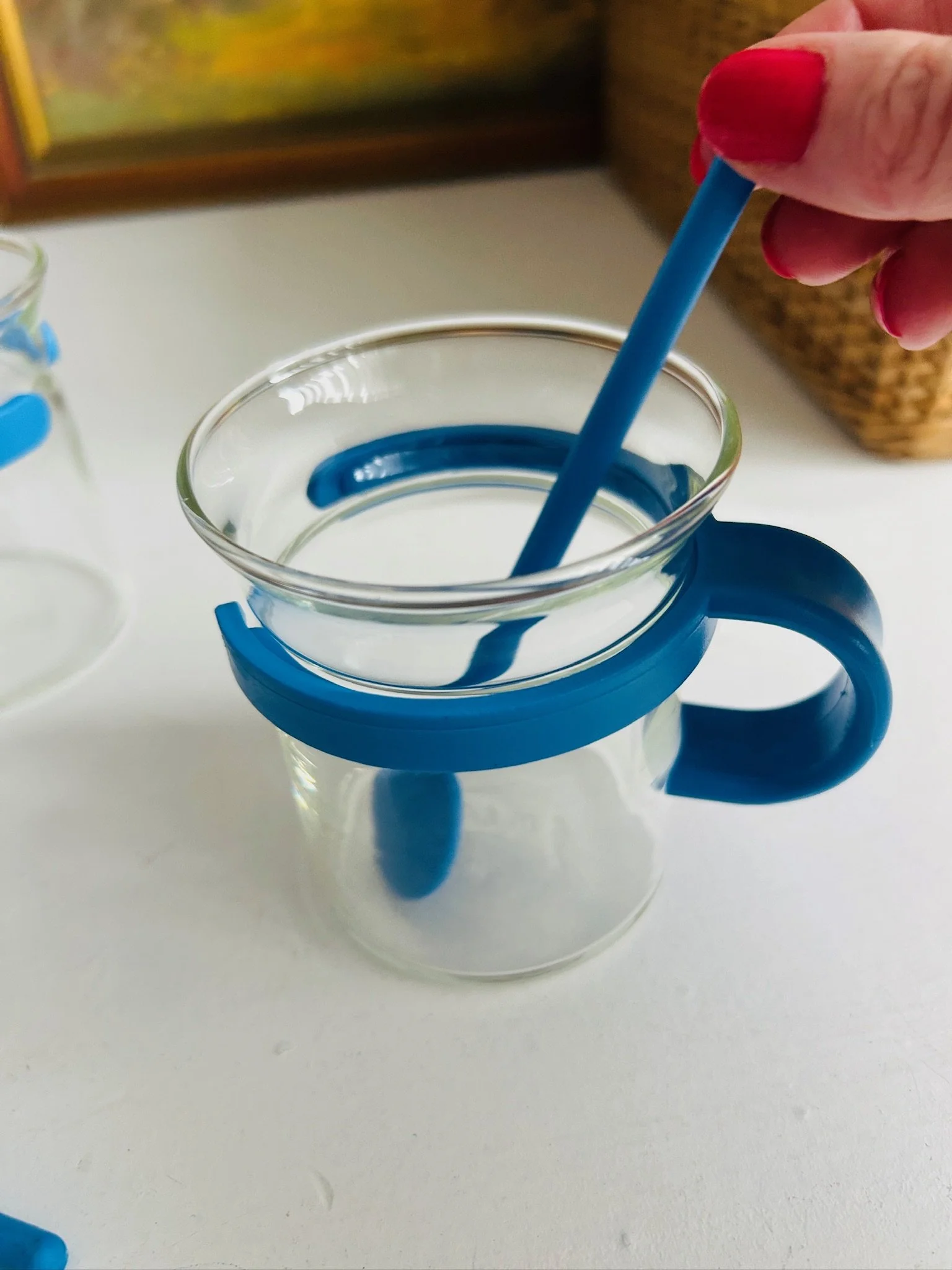 Close-up of a single blue Bodum Picard cup with spoon resting inside, showing the rounded handle and flared glass rim.