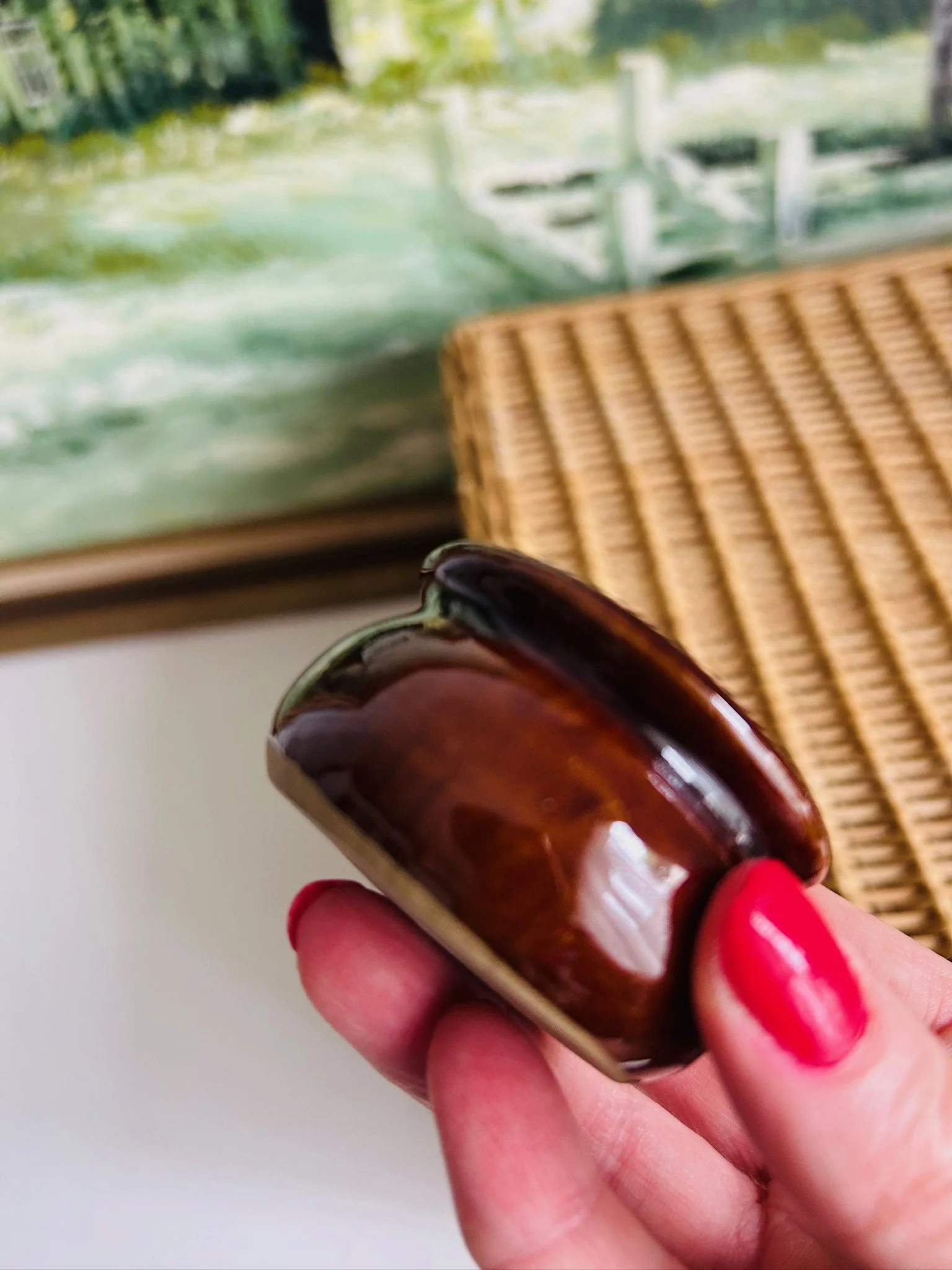 Close-up of the lower side of the pot resting in hand, showing the glossy brown glaze and pale base ring