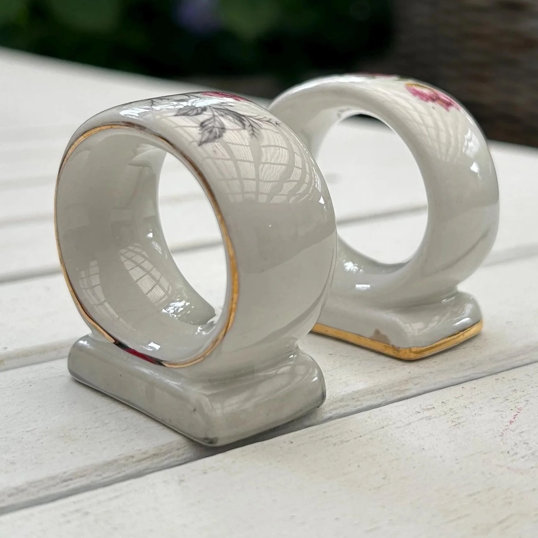 Side view of both napkin rings showing gold trim and floral design