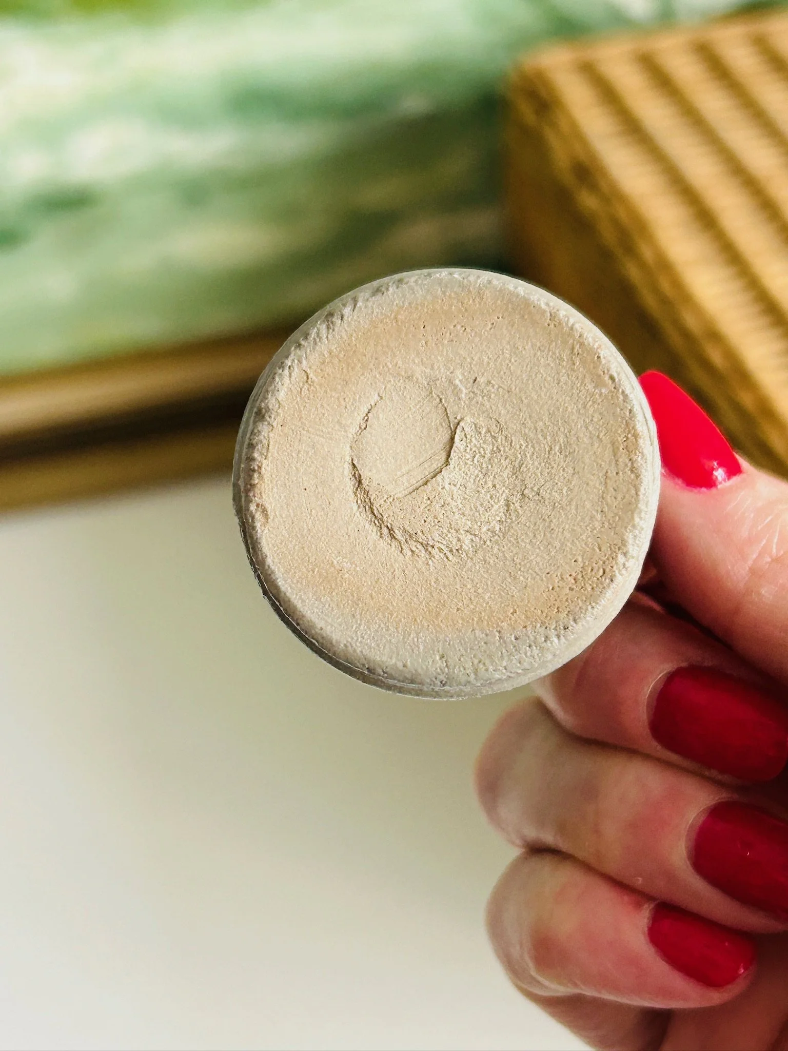 Underside of the unmarked salt cellar held in hand, showing the plain stoneware base with circular throwing mark