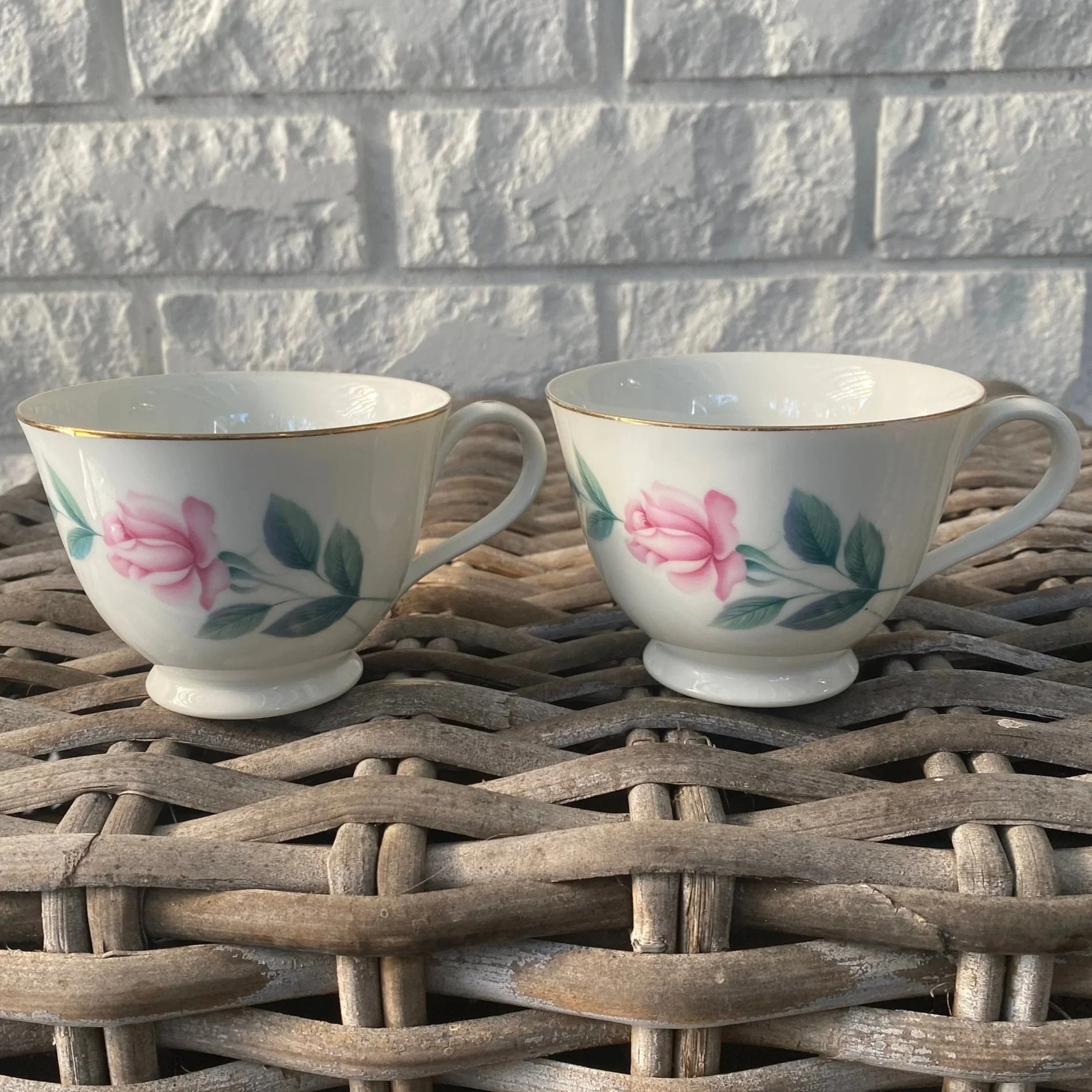Pair of Noritake Anita teacups side-by-side on wicker with rose motif
