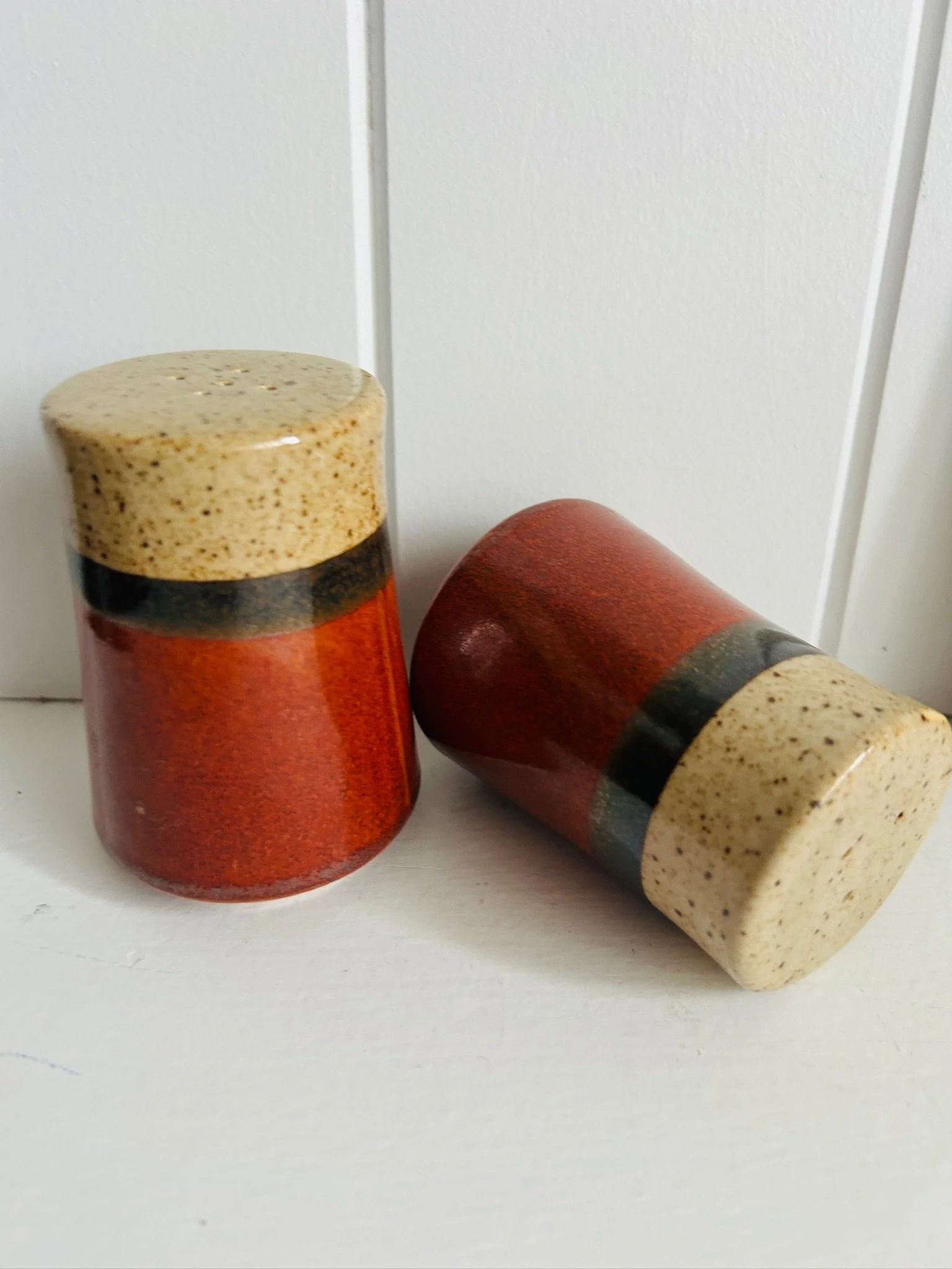 Pair of Japanese ceramic shakers with one standing upright and one lying on its side against a white background.