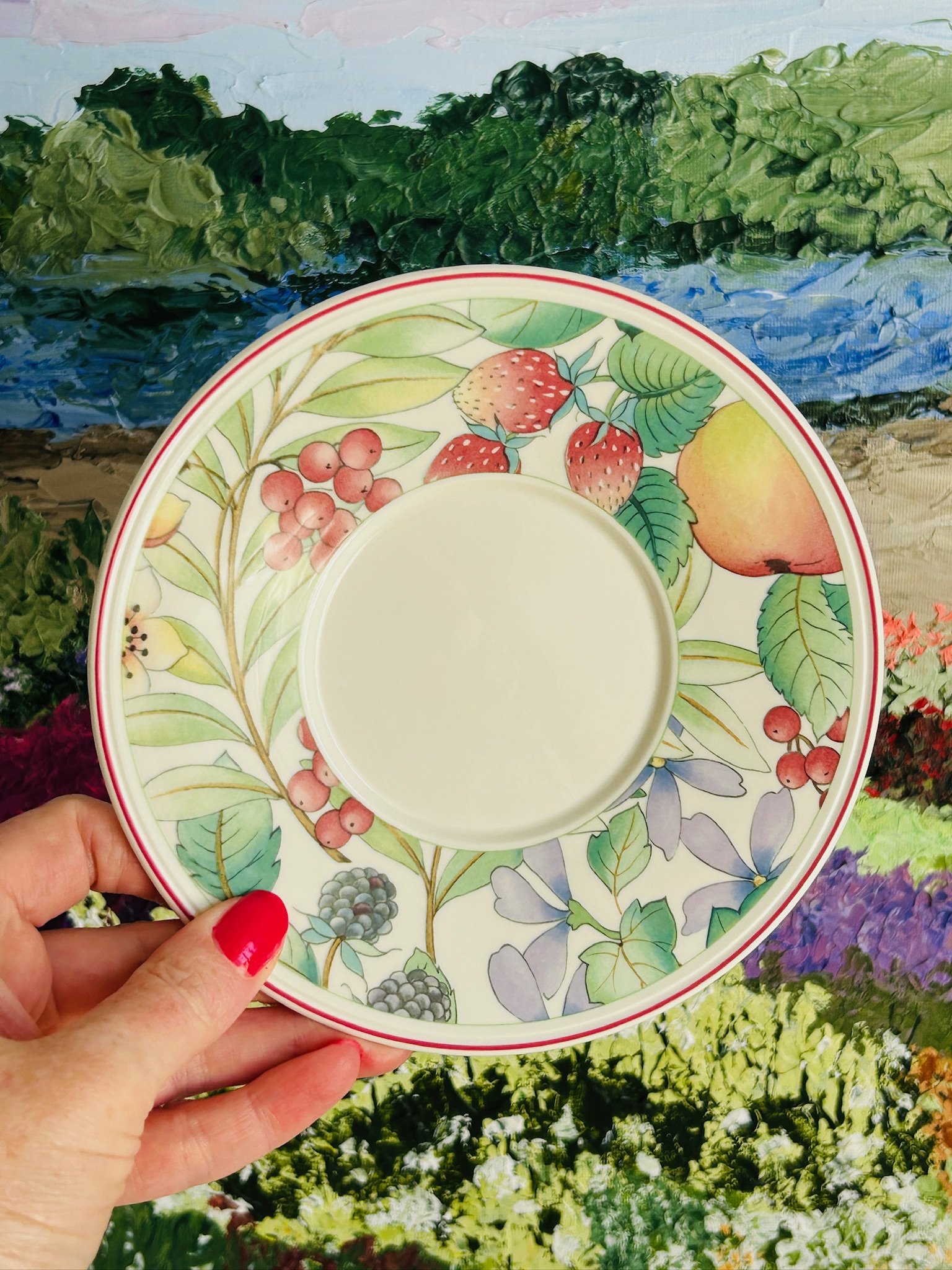 Top view of the Catalina saucer held in hand, showing the berry, leaf, and floral border with a red rim.
