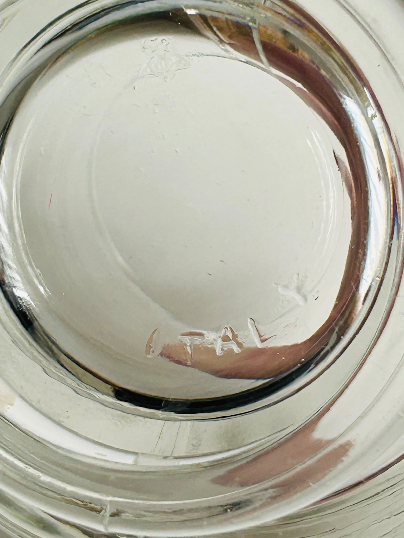 Underside view of the vintage Arno glass creamer showing the clear pressed glass base and central pontil-style formation