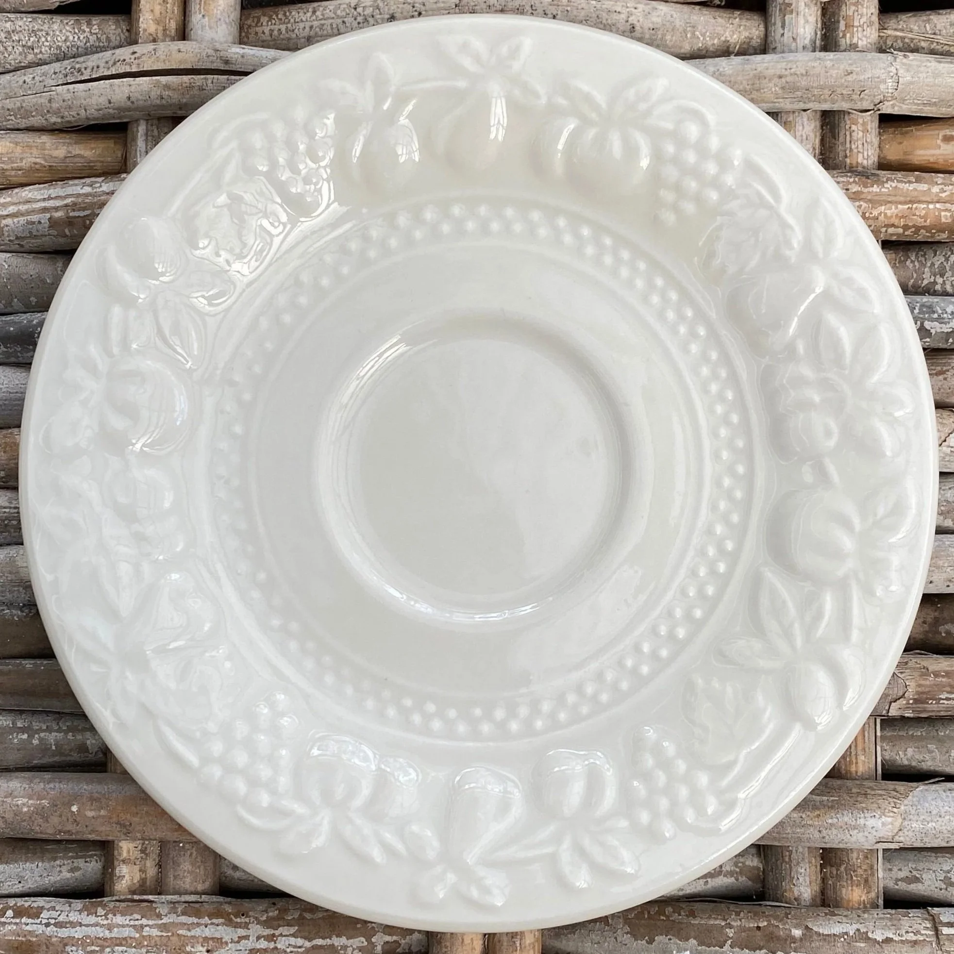 Close-up of a single saucer showing full fruit and leaf embossed rim