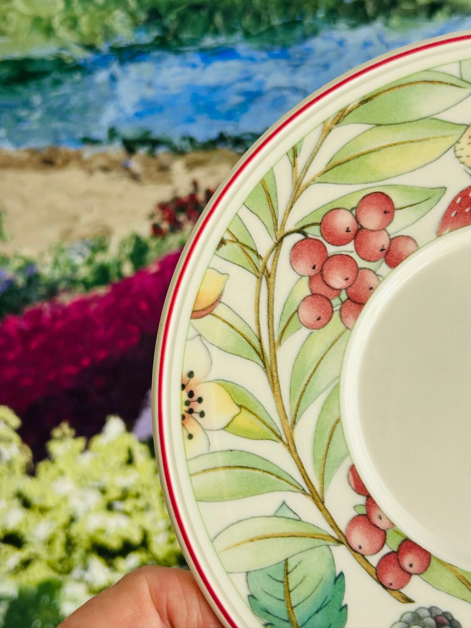 Close-up of the saucer pattern showing red berries, green leaves, and fine line detail around the well.