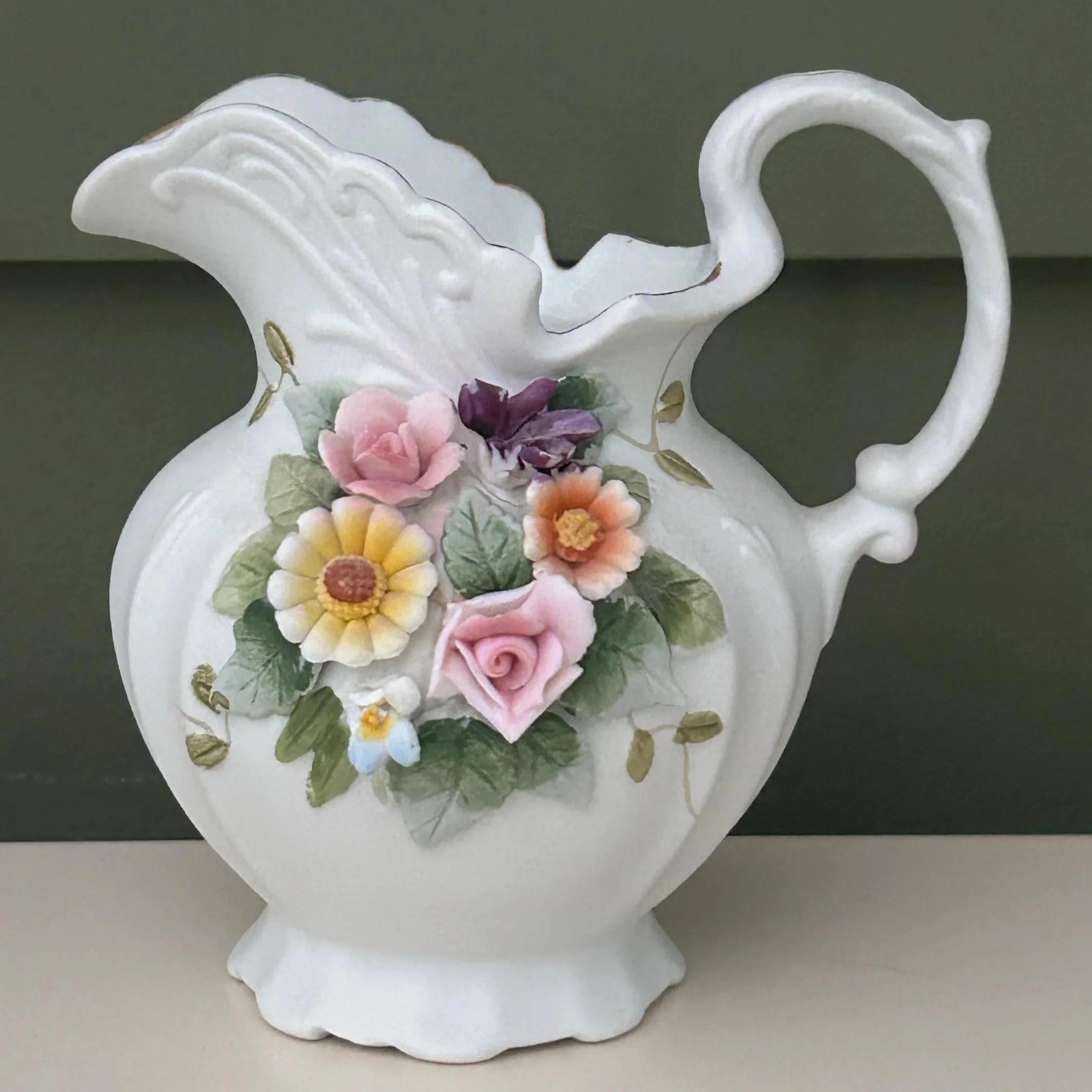 Hand-painted floral jug showing pastel roses and leaves on white ceramic