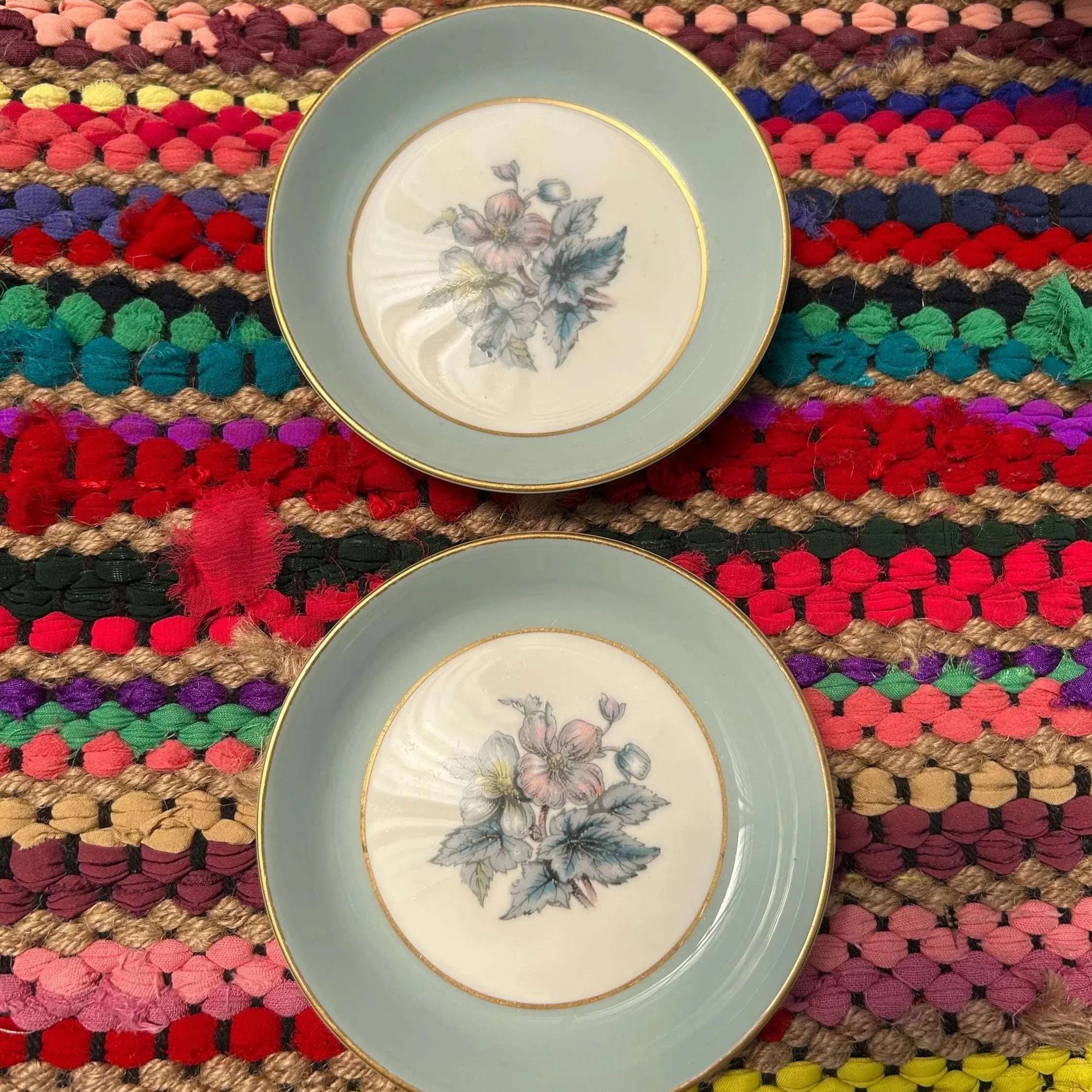 Two Royal Worcester ring dishes with Woodland floral design on a textured woven mat