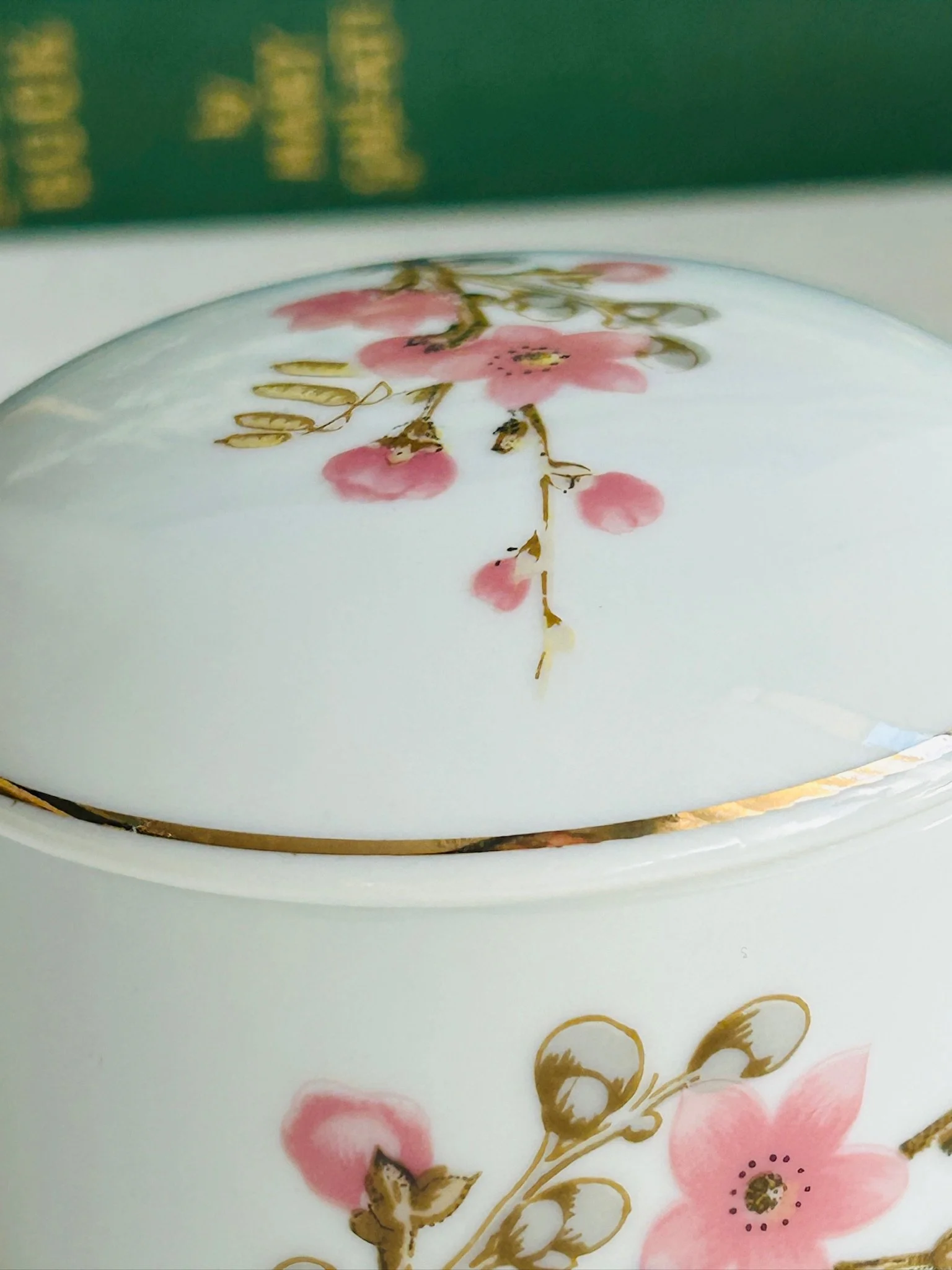 Close-up of the lid resting on the bowl, showing the pink blossom pattern and gold rim detail