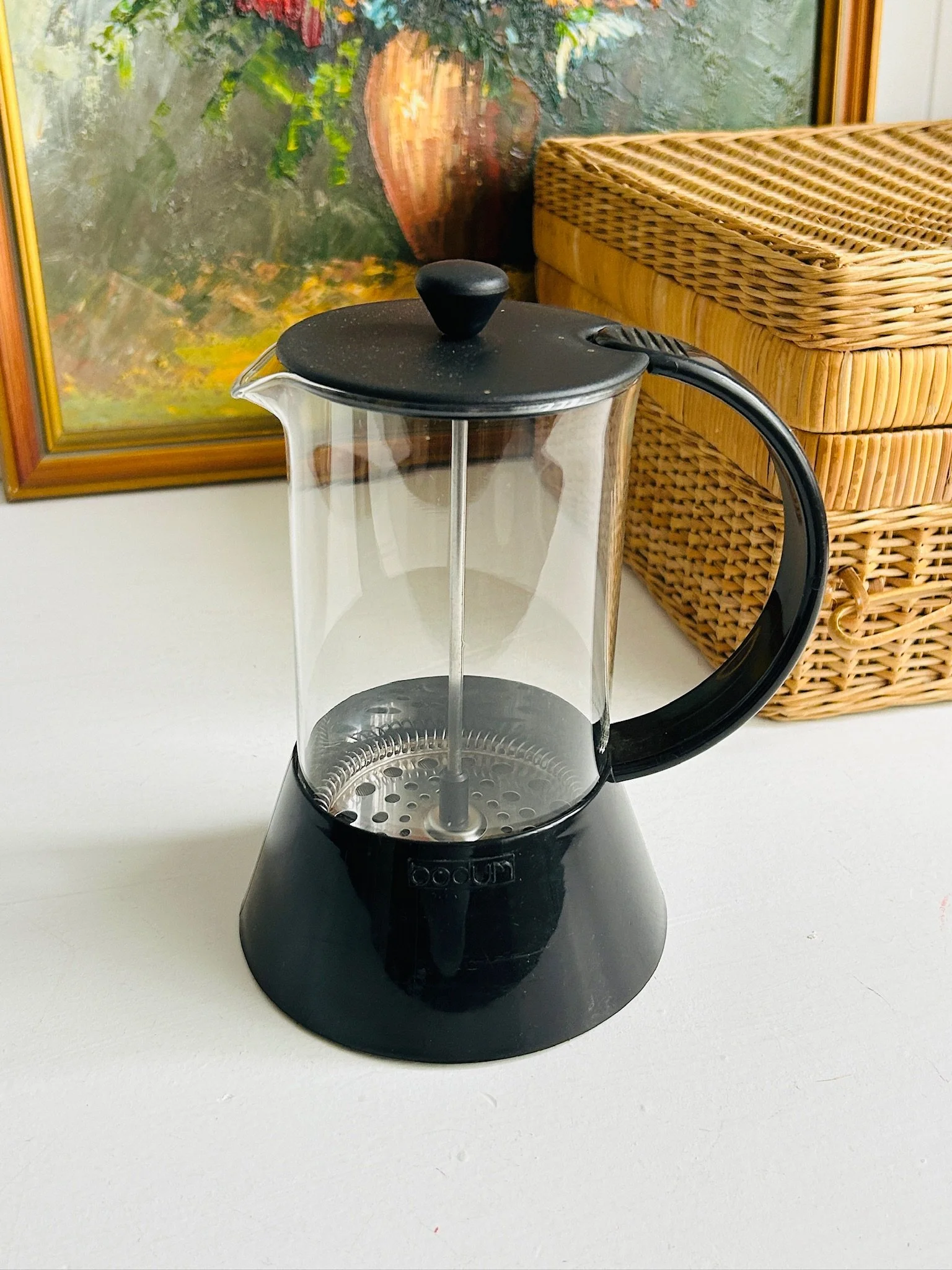 Front view of vintage Bodum Presso French press with clear borosilicate glass carafe, black plastic frame, black lid, and plunger knob.