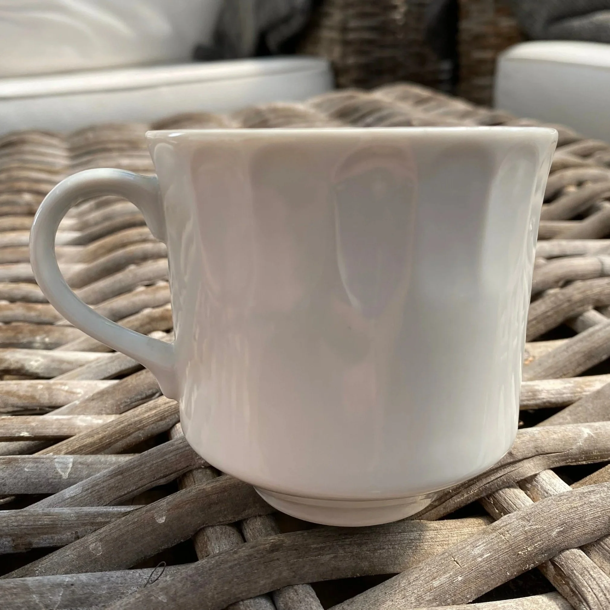 Angled side view of vintage white cup with handle and ribbed body