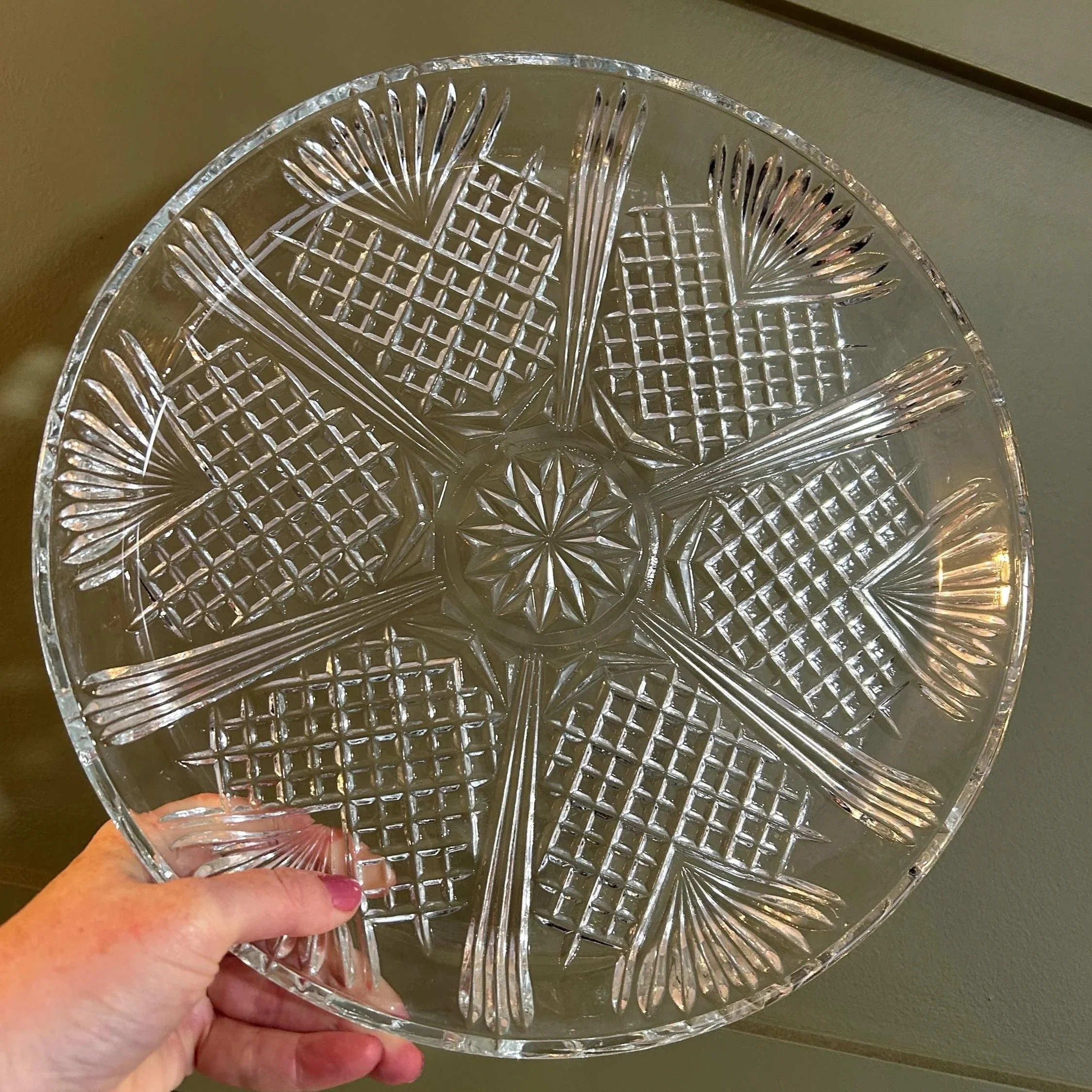 Hand holding large round Italian cut crystal platter with starburst centre.
